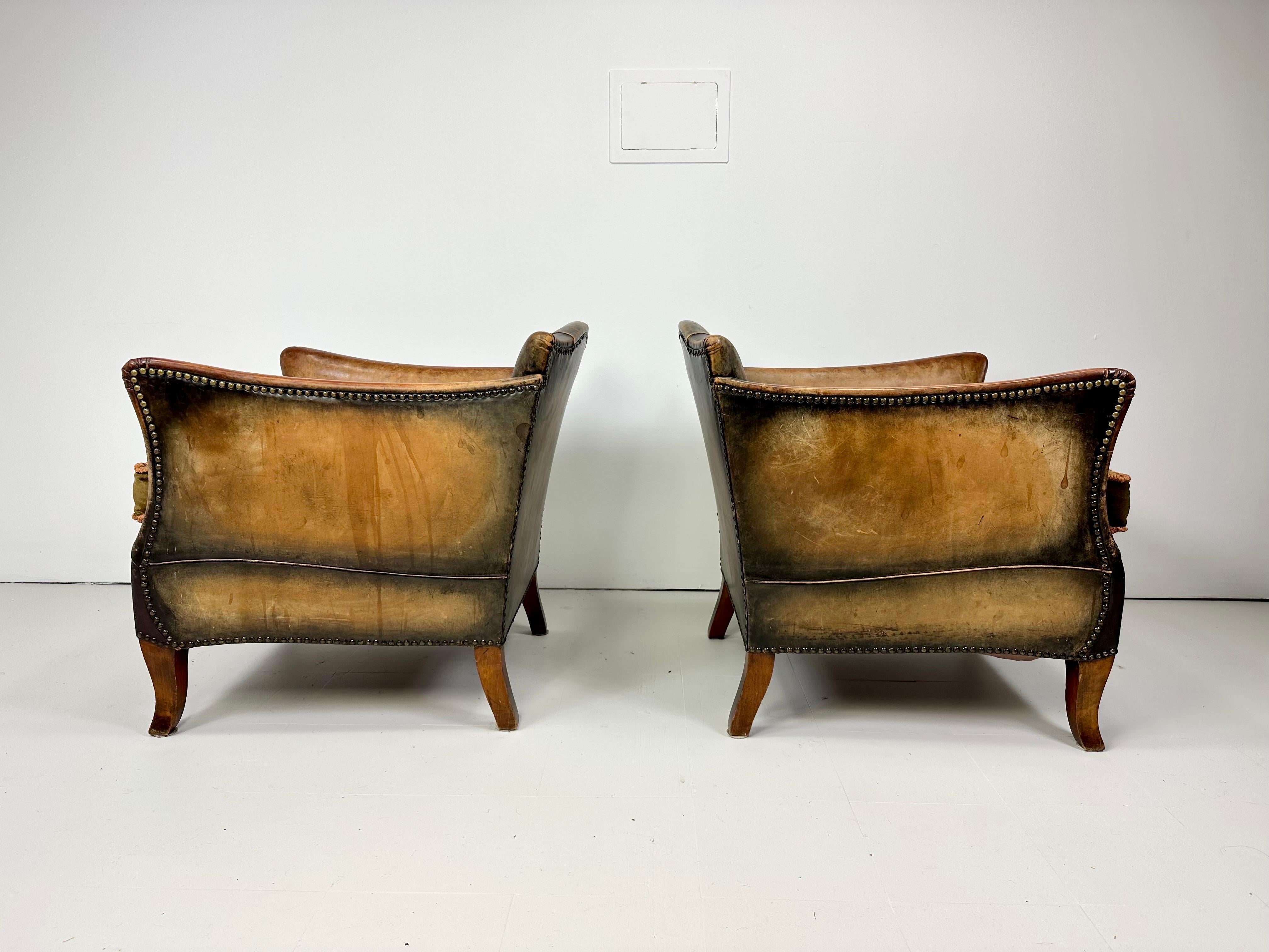 Pair of 1930’s European Leather Lounge Chairs. Original leather patina with nailhead details. Reupholstered velvet seat cushion.