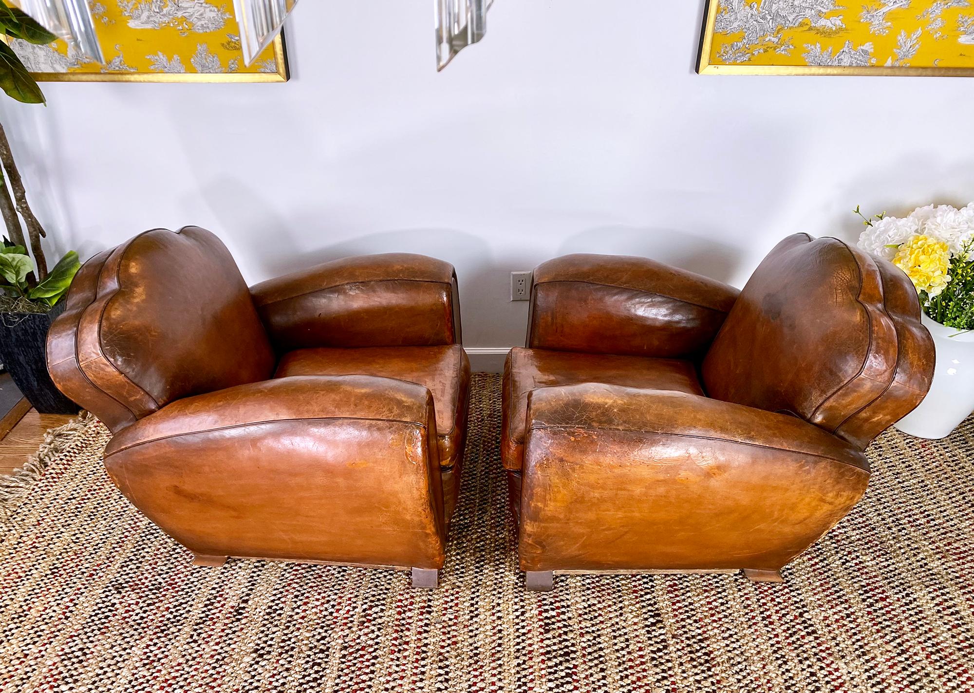 Pair of Classic 1940s French Art Deco club chairs in brown leather. Upholstered in beautifully patinated in their original calfskin leather. Sloping back. Solid frame. As very comfortable as they look.