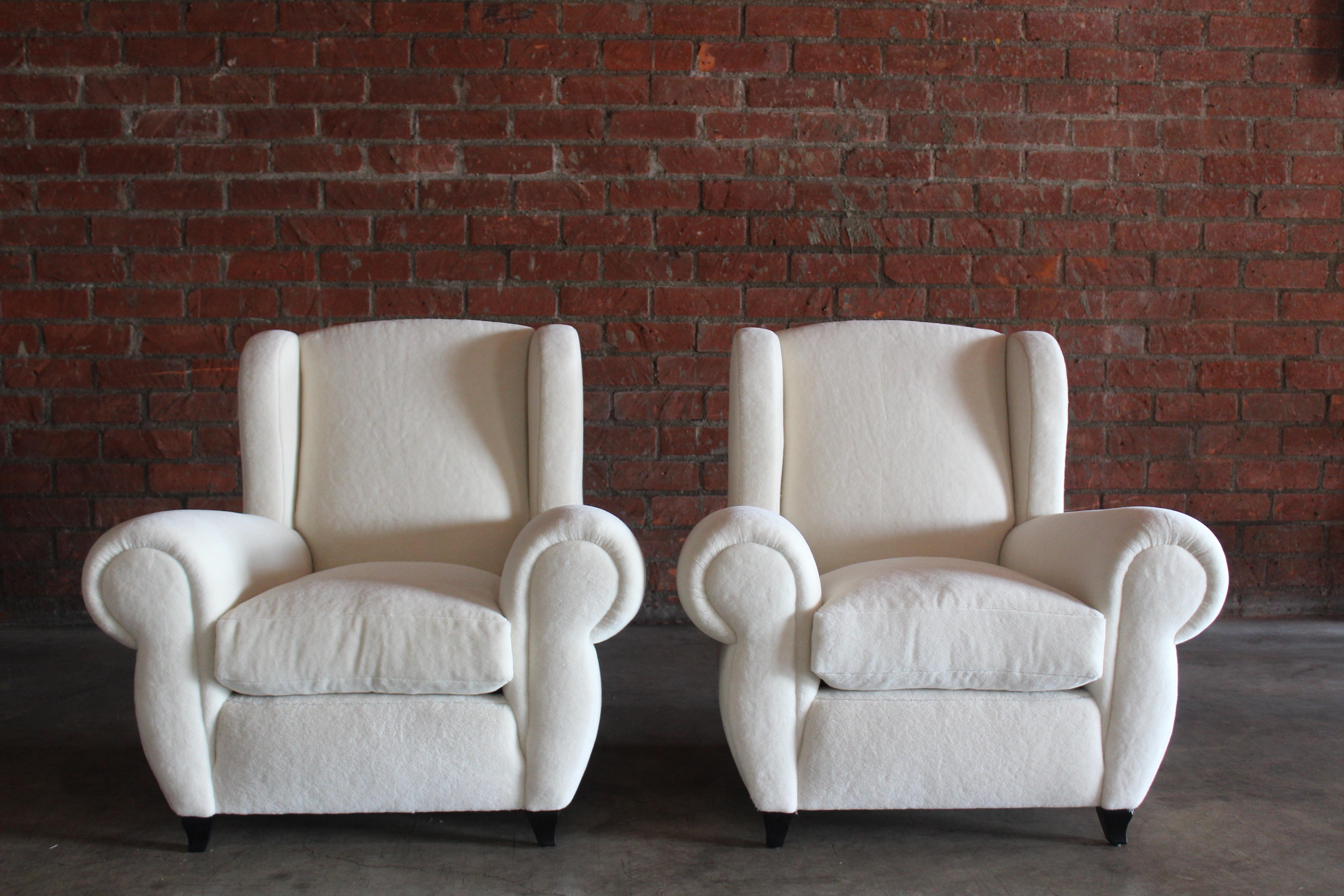 Pair of oversized 1930s Maurice Rinck styled French Art Deco club chairs. The pair have been completely restored. They have been reupholstered in an alpaca wool. The legs have been refinished satin black. In overall excellent condition. Sold as a