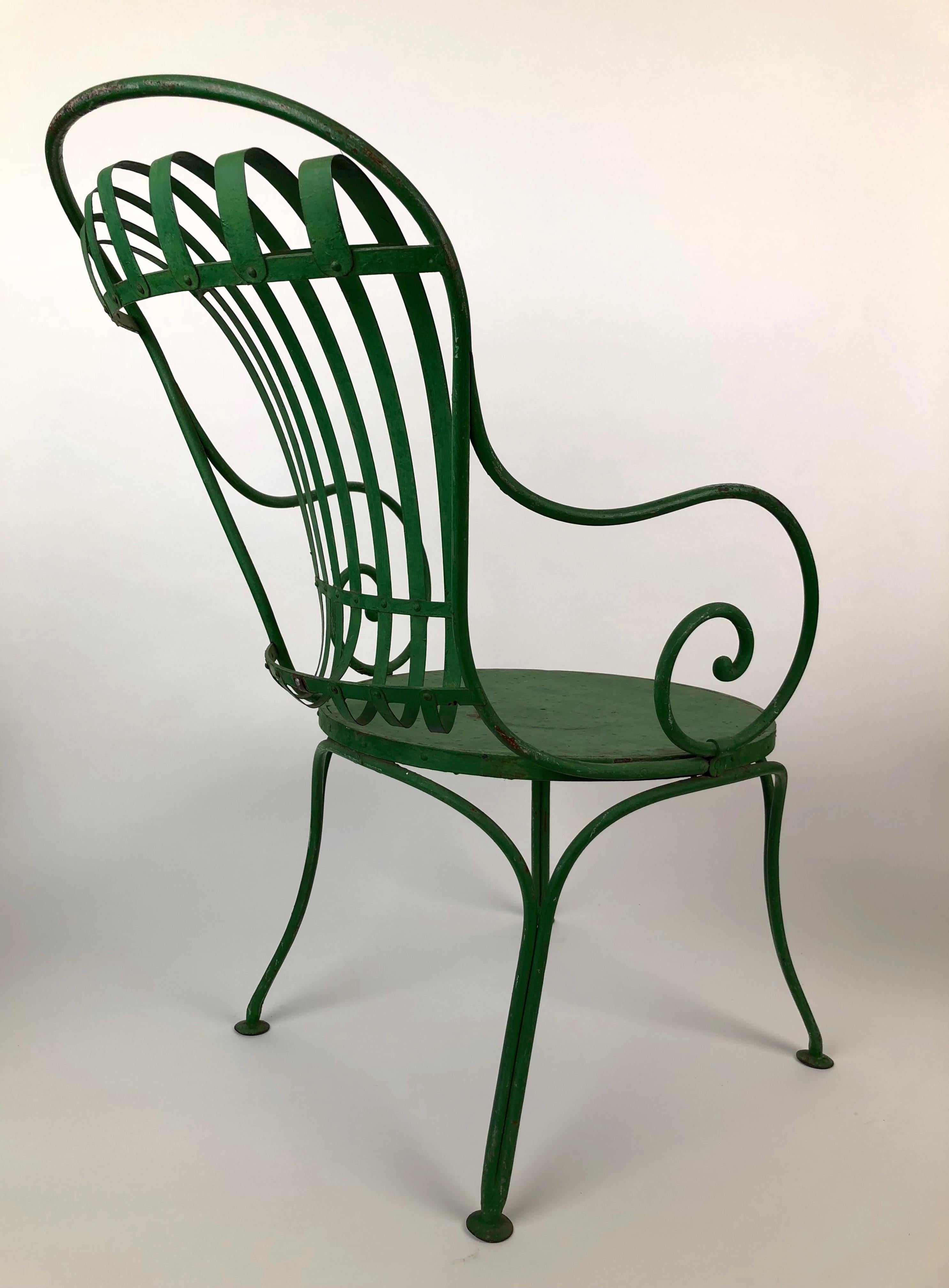 An unusual pair of green, 1930s French metal garden chairs from Francois Carre. They feature a solid steel seat with a spring steel fan back, the color is original with a wonderful patina. The frame of the chair is wrought iron. They are in original