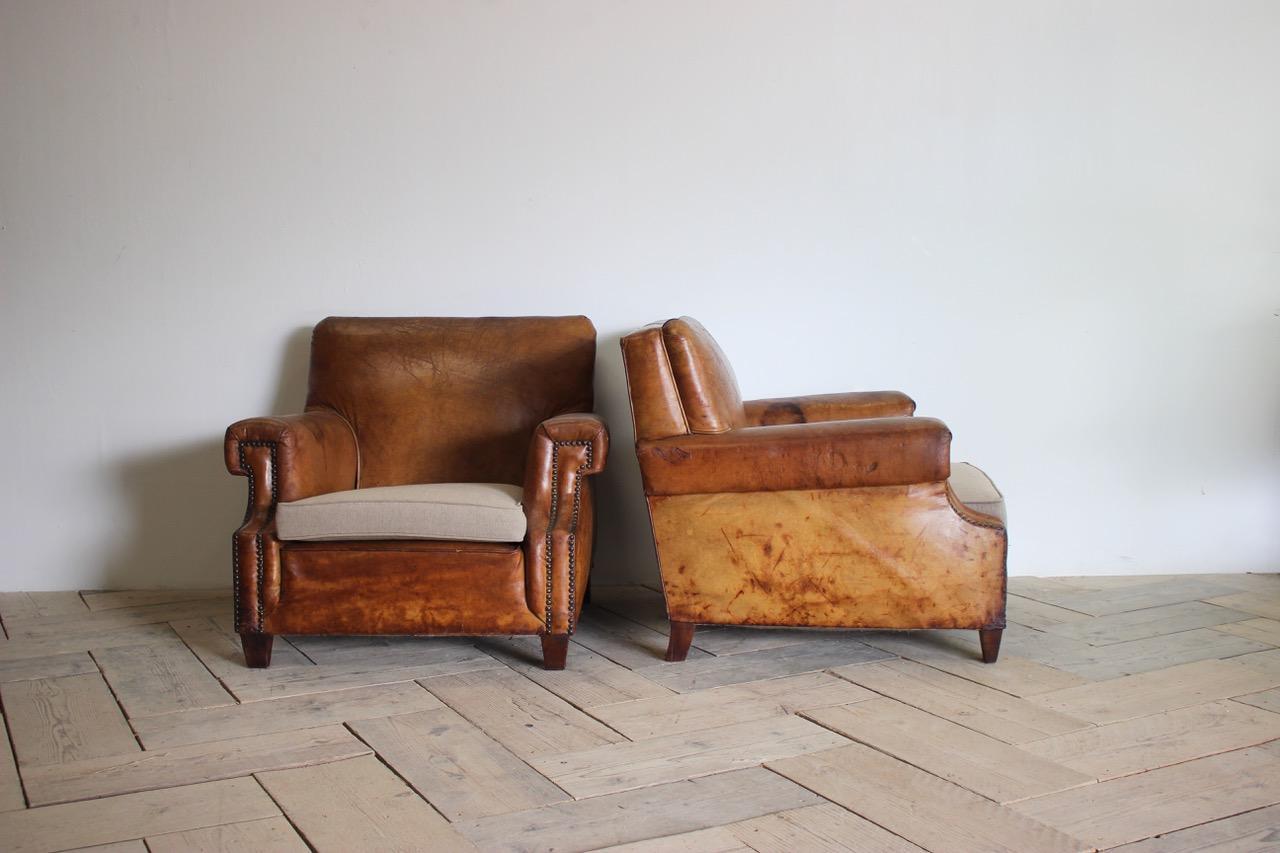 A handsome pair of circa 1930s French leather armchairs, retaining the original leather, with a lovely colour and with foam cushions, covered in linen. 

France 

Measurements: 40cm high (Floor to seat).