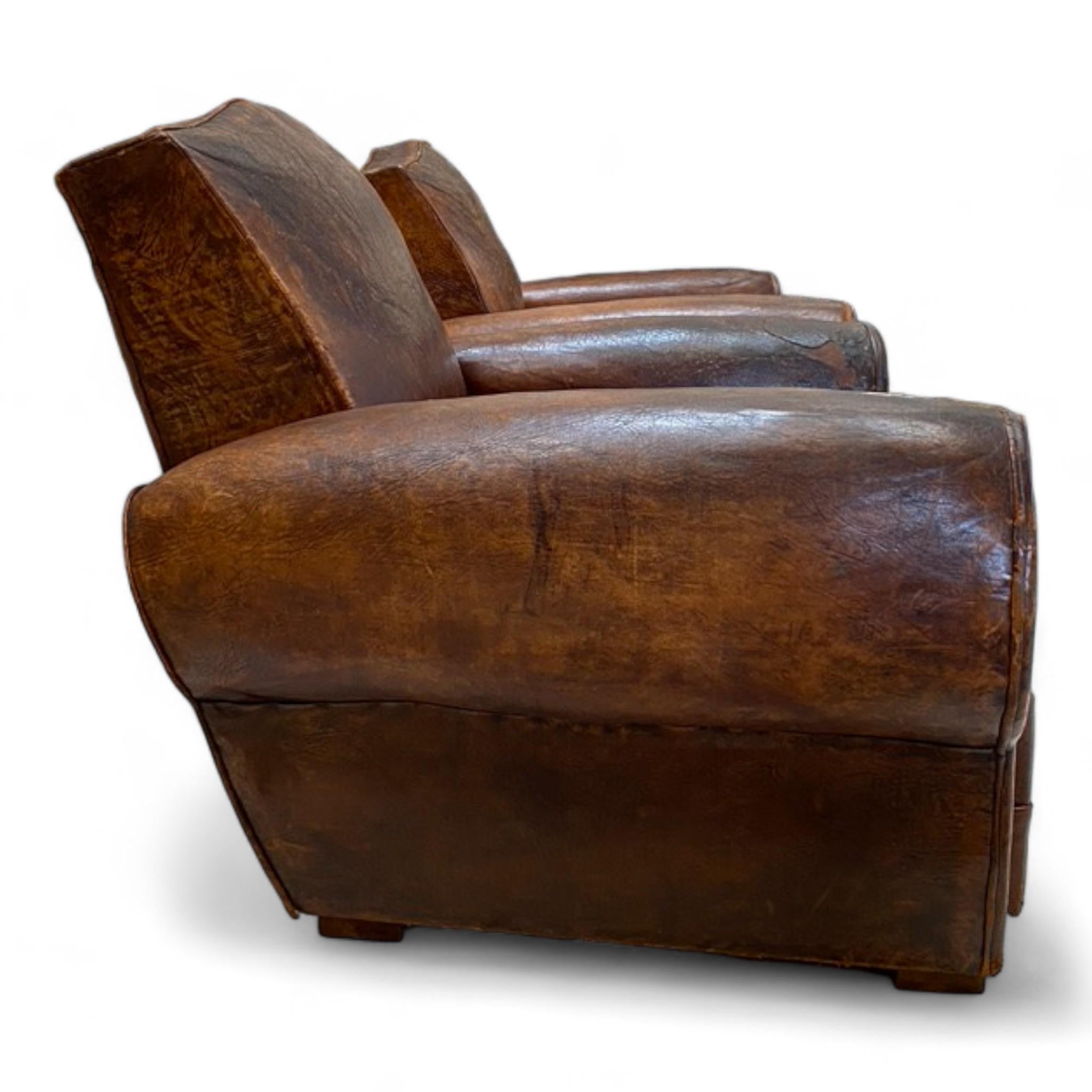 These 1930s French Leather Club Chairs are upholstered with high quality leather in good vintage condition with well-worn character. 
Featuring iconic cigar style arms and unique moustache-shaped back, these chairs are always a favorite among