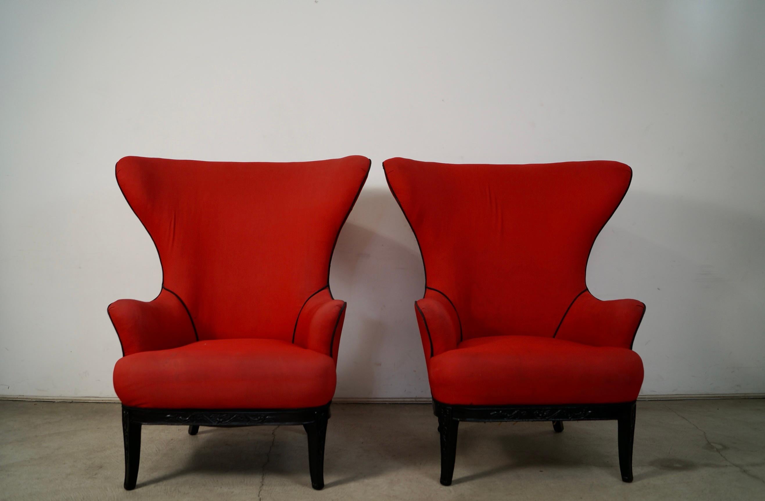 Paire de fauteuils à oreilles anciens à vendre. Ils ont un magnifique dos en aile de papillon et sont très solides. Ils ont une base en bois massif dans une finition ébène foncée, et ont été précédemment retapissés dans un tissu rouge avec des