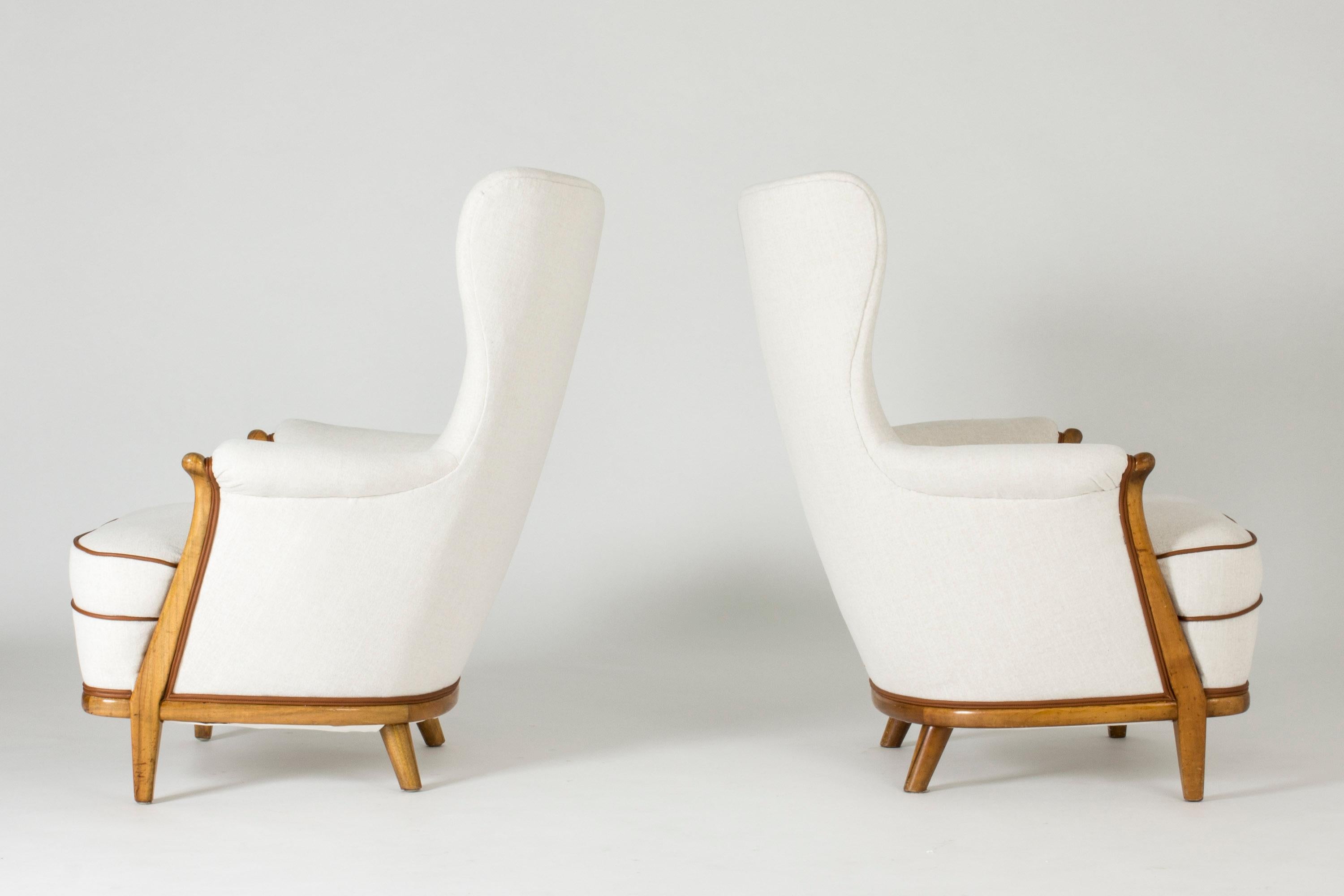 Pair of elegant lounge chairs by Gustaf Allert, made by master carpenter in 1939. Elegant broad backs with leather dressed buttons and walnut lining the base and the fronts of the armrests. The chairs are upholstered with double rows of leather