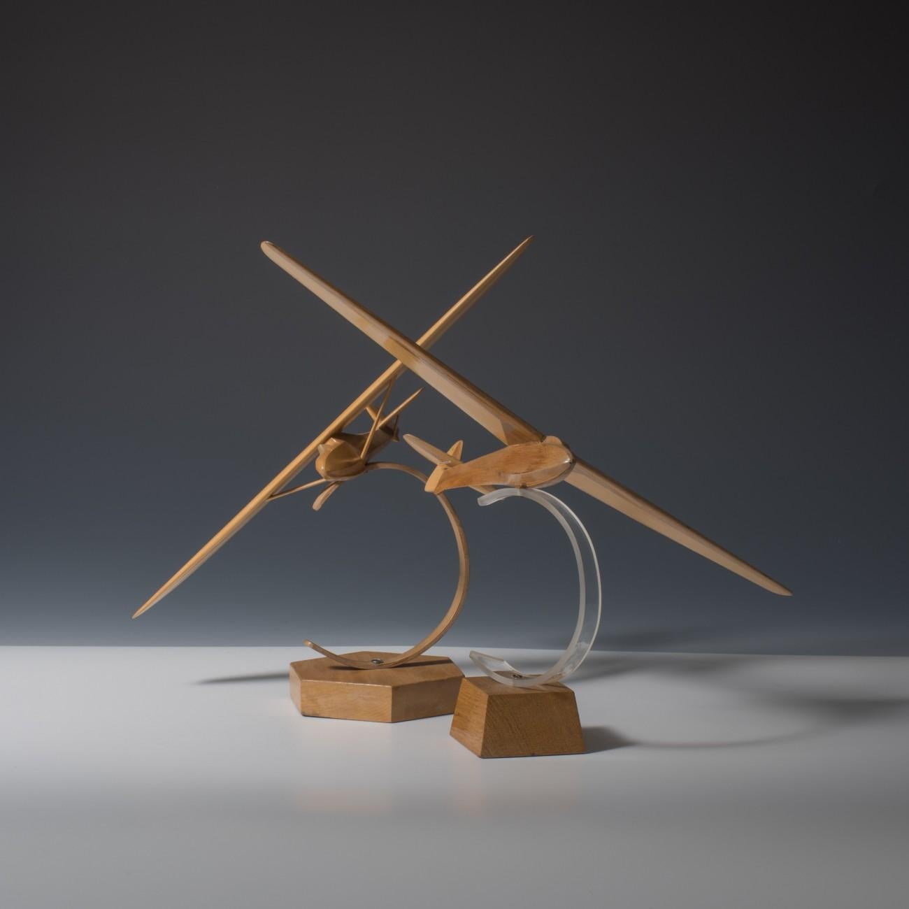 Two finely carved, laminated wooden models of gliders from one of the German airfields such as Oerlinghausen or Scharfoldendorf. The larger model is mounted on a Perspex stand that sits on a wooden base and the smaller one is mounted on an all wood