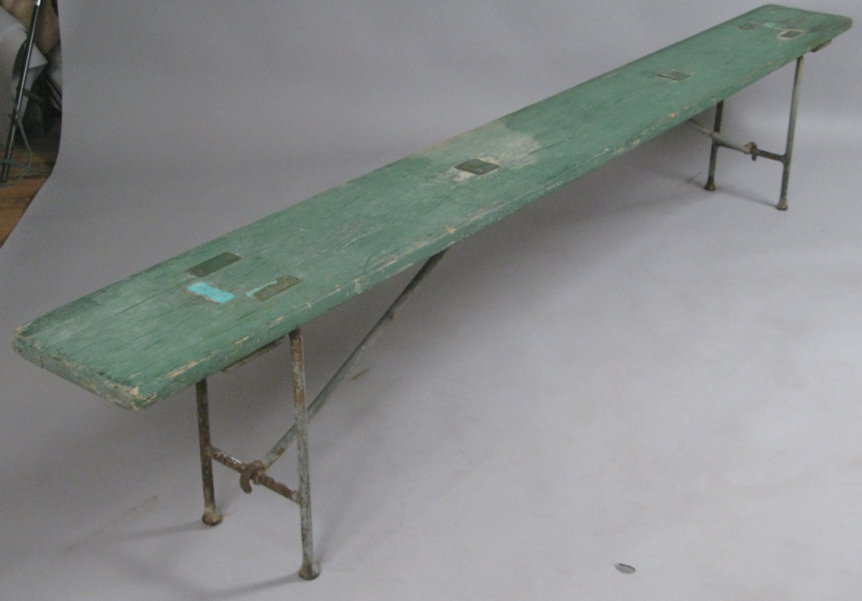 This rare pair of Naval benches were used in the banquet rooms on aircraft carriers in the 1930s. This pair has their original aged green painted finish on the pine benches. Unique design with exposed brass fitting panels on the top. Iron legs fold