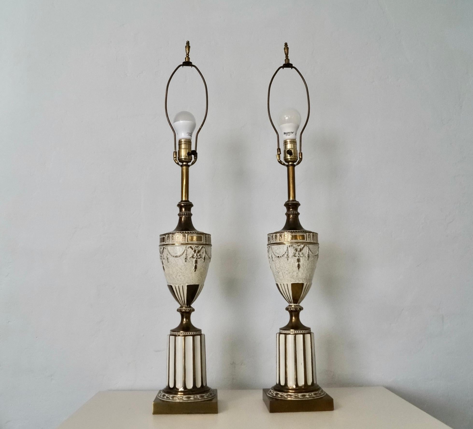 Pair of vintage ancient Roman Neoclassical inspired table lamps for sale. Made of solid brass and metal, and are quite beautiful. They are in excellent original condition with some patina to the brass. They are an antique white tone and brass with