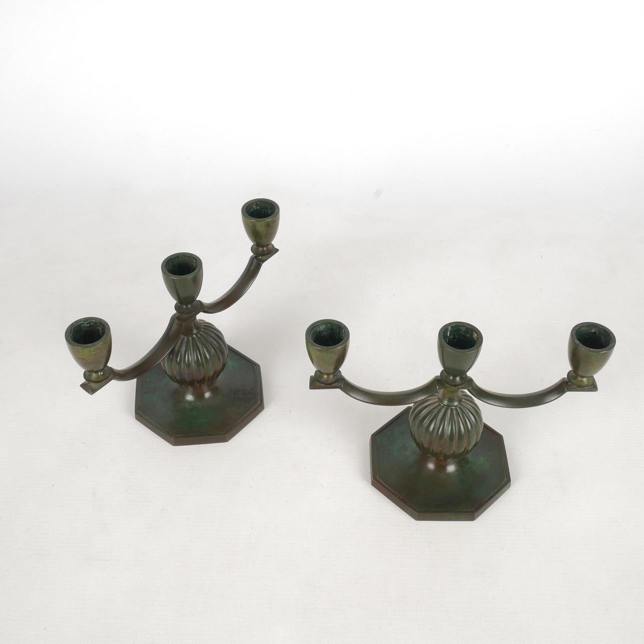 Un'eccezionale e rara coppia di candelabri a tre bracci disegnati da Jacob Ängman per la rinomata azienda svedese GAB (Guldsmedsaktiebolaget), intorno agli anni Trenta. Questi pezzi scultorei sono realizzati in bronzo massiccio con una patina