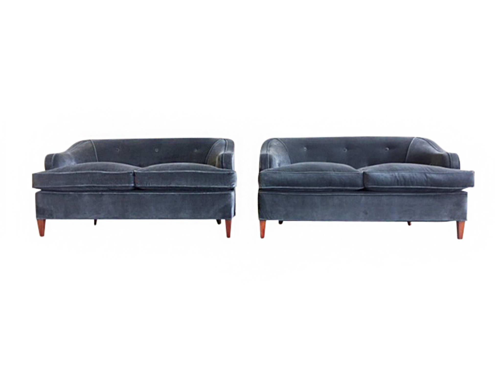 These 1930s Art Deco settees are newly reupholstered in a smoky blue brushed velvet. The fabric is soft and covers new down cushions, creating an ideal immersive surface for comfort and rest. With clean lines and rounded edges, the sofas strike a