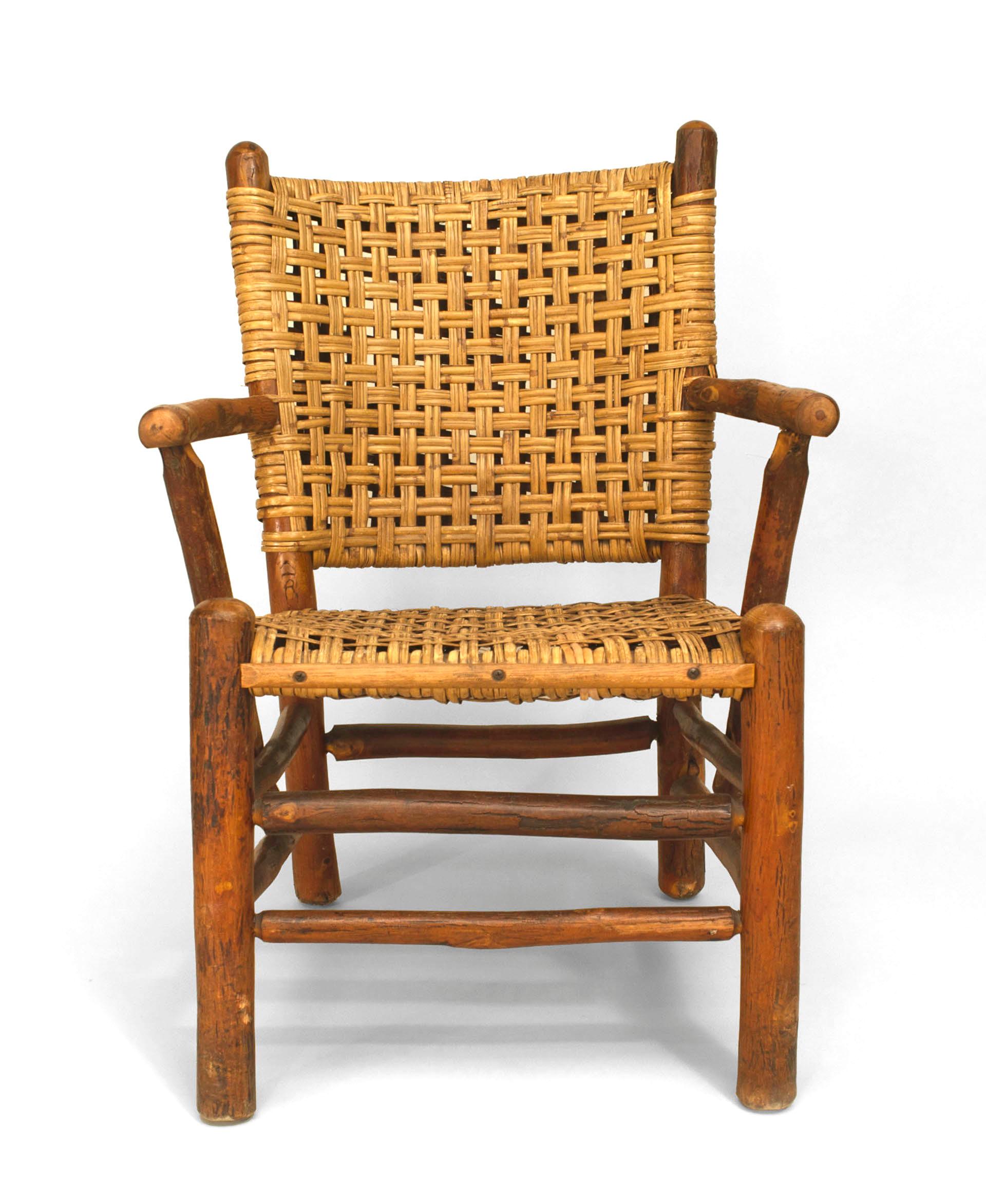 Branded with the name of the Old Hickory Company of Martinsville, Indiana, this pair of rustic open armchairs features woven seats and backs above double box stretchers.