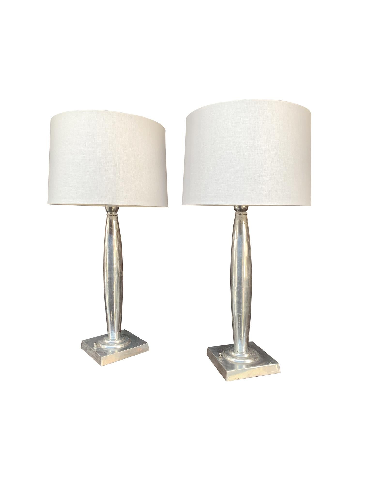 A brilliant pair of aluminum Art Deco table lamps crafted in the 1940s. We love their lustrous surface and streamlined forms. New custom linen shades in an ecru tone complement the aluminum, creating an overall elegant look. The lamps are newly