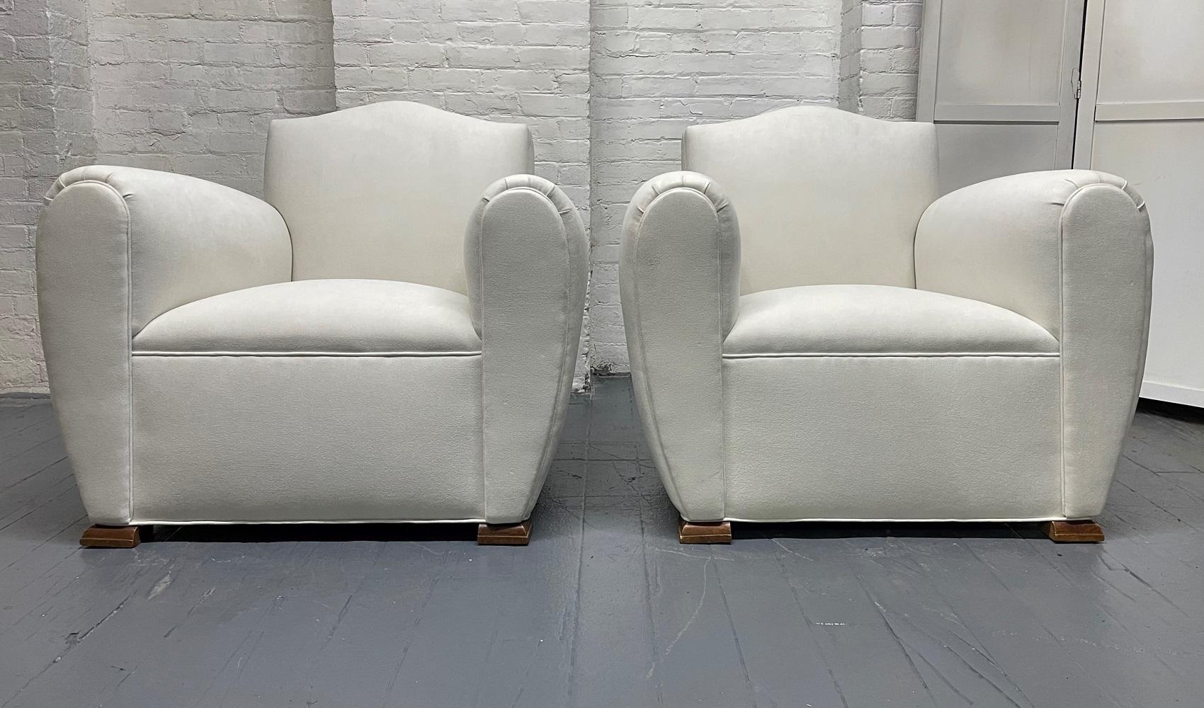 Pair of 1940s Art Deco newly upholstered lounge chairs. The chairs have solid walnut bracket feet, and the chairs are oversized.
