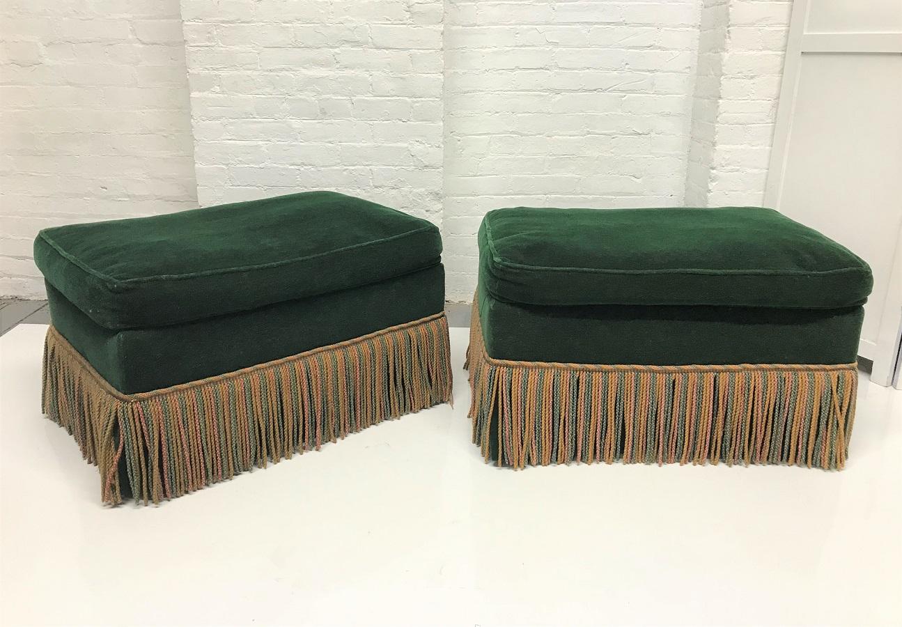 Pair of 1940s Art Deco green velvet upholstered ottomans. The ottomans have fringed skirts and the original velvet fabric.  There is a pair of matching lounge chairs listed and sold separately. 