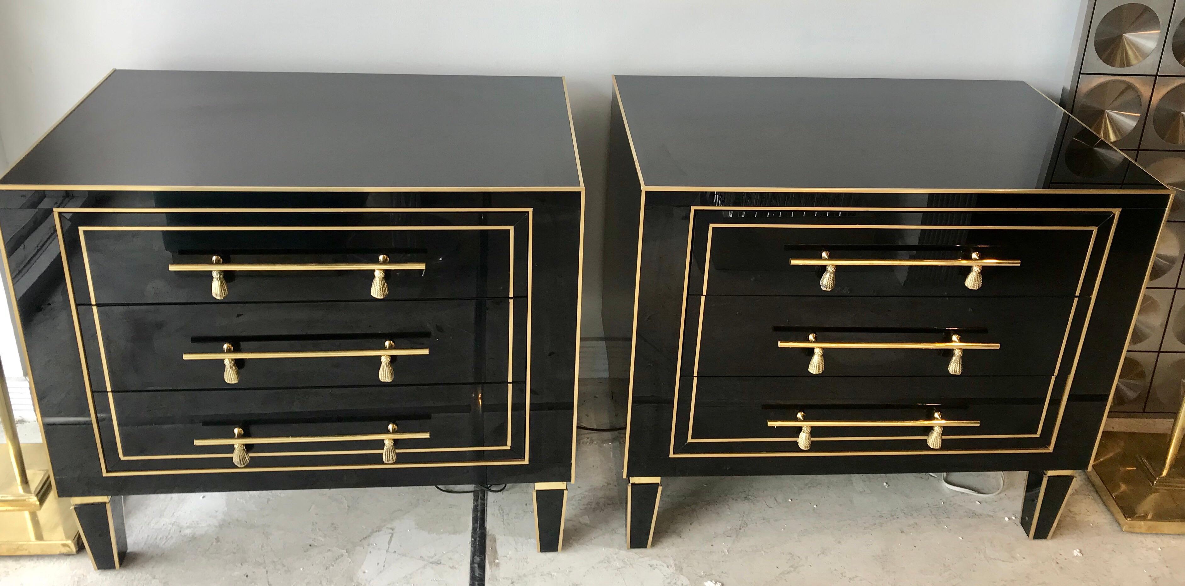 A fabulous pair of glamorous Italian black glass and brass side/ bed side chests with brass tassel pulls.