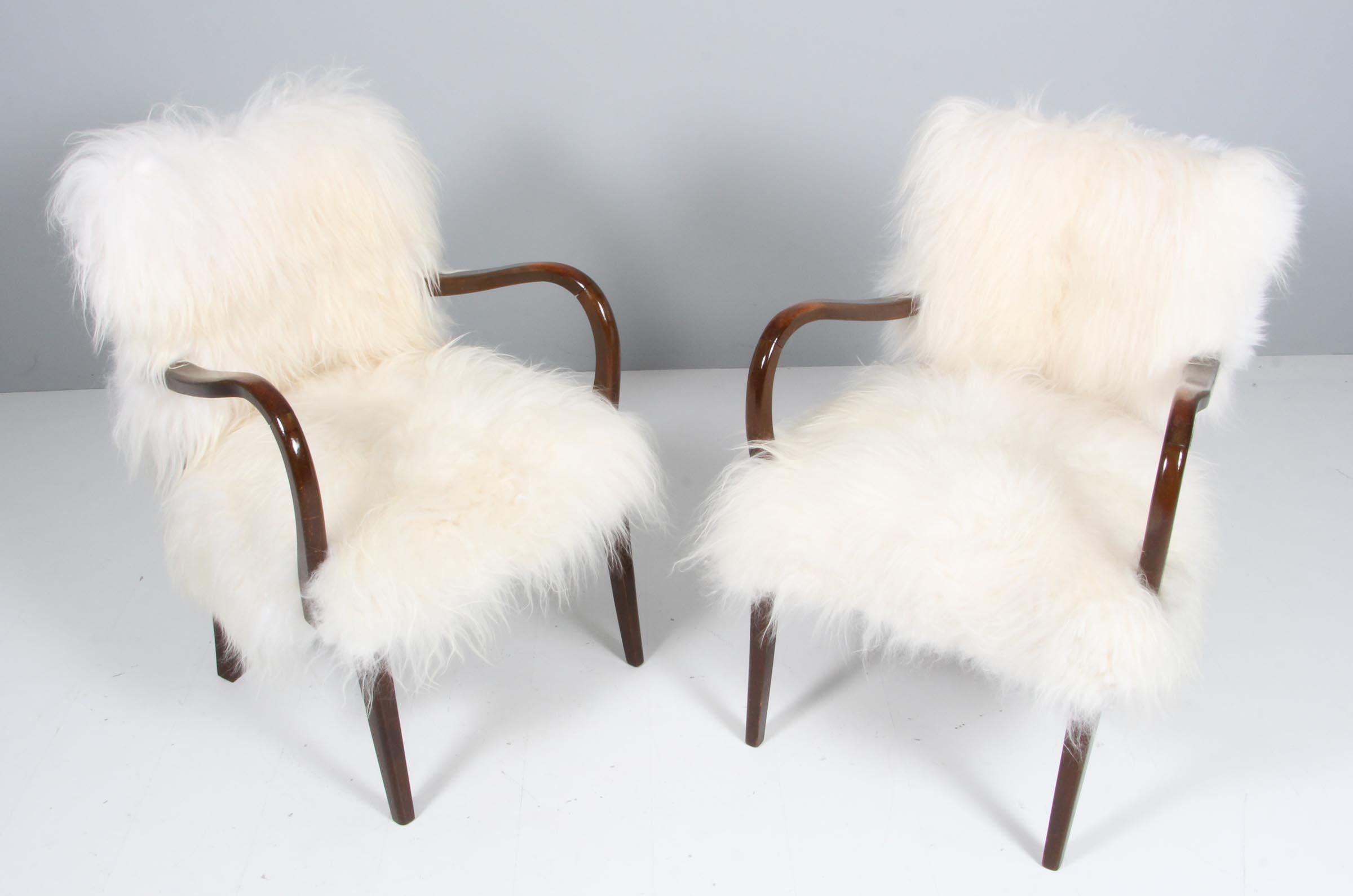 Pair of chairs from the 1940s new upholstered with longhaired lambskin.

Frame of stained beech.
