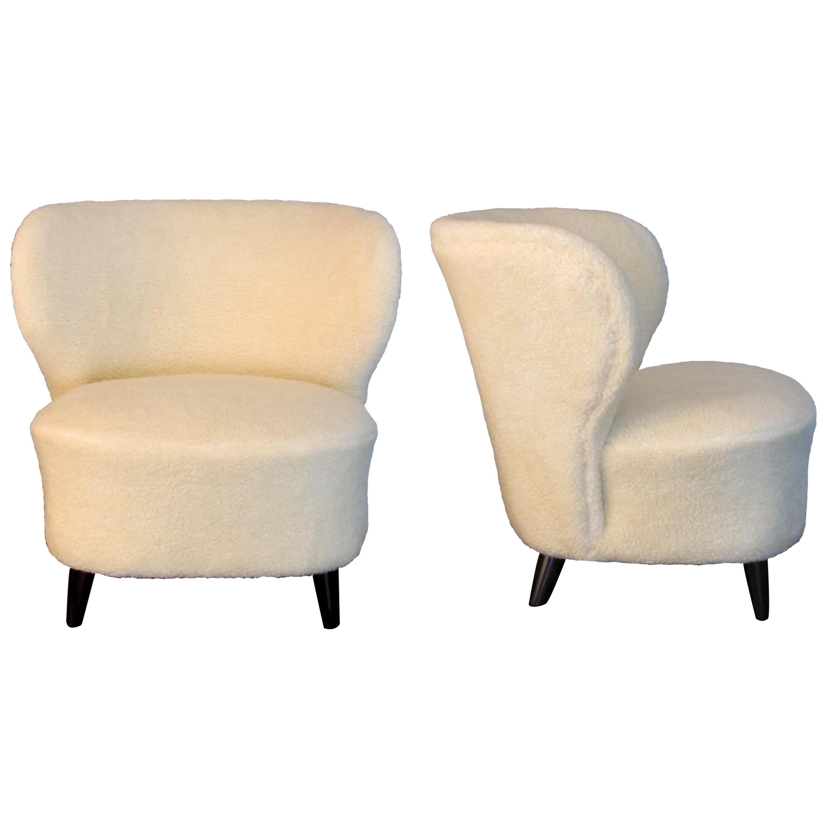 Pair of 1940s deep-seated armchairs with a very generous curved wing backrest. These Scandinavian armchairs have good proportions are well-padded and very comfortable. These armchairs have been newly reupholstered in a really soft lambskin mix