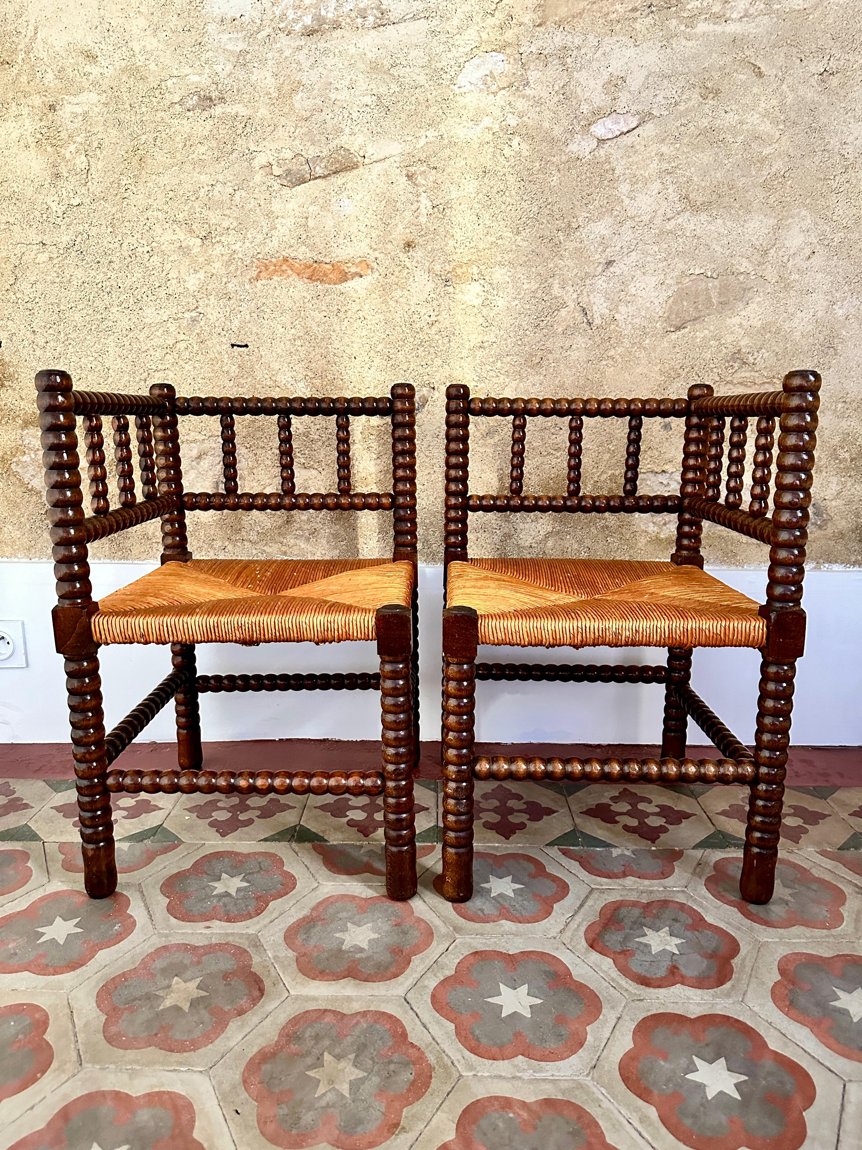 Pair of 1940s French bobbin corner chairs.

Wonderful turned oak 'coin de feu' chairs with rush seats and a varnished finish. In excellent, solid condition with very light wear.

Height 64cm Width 41cm Depth 41cm Seat Height 36cm
