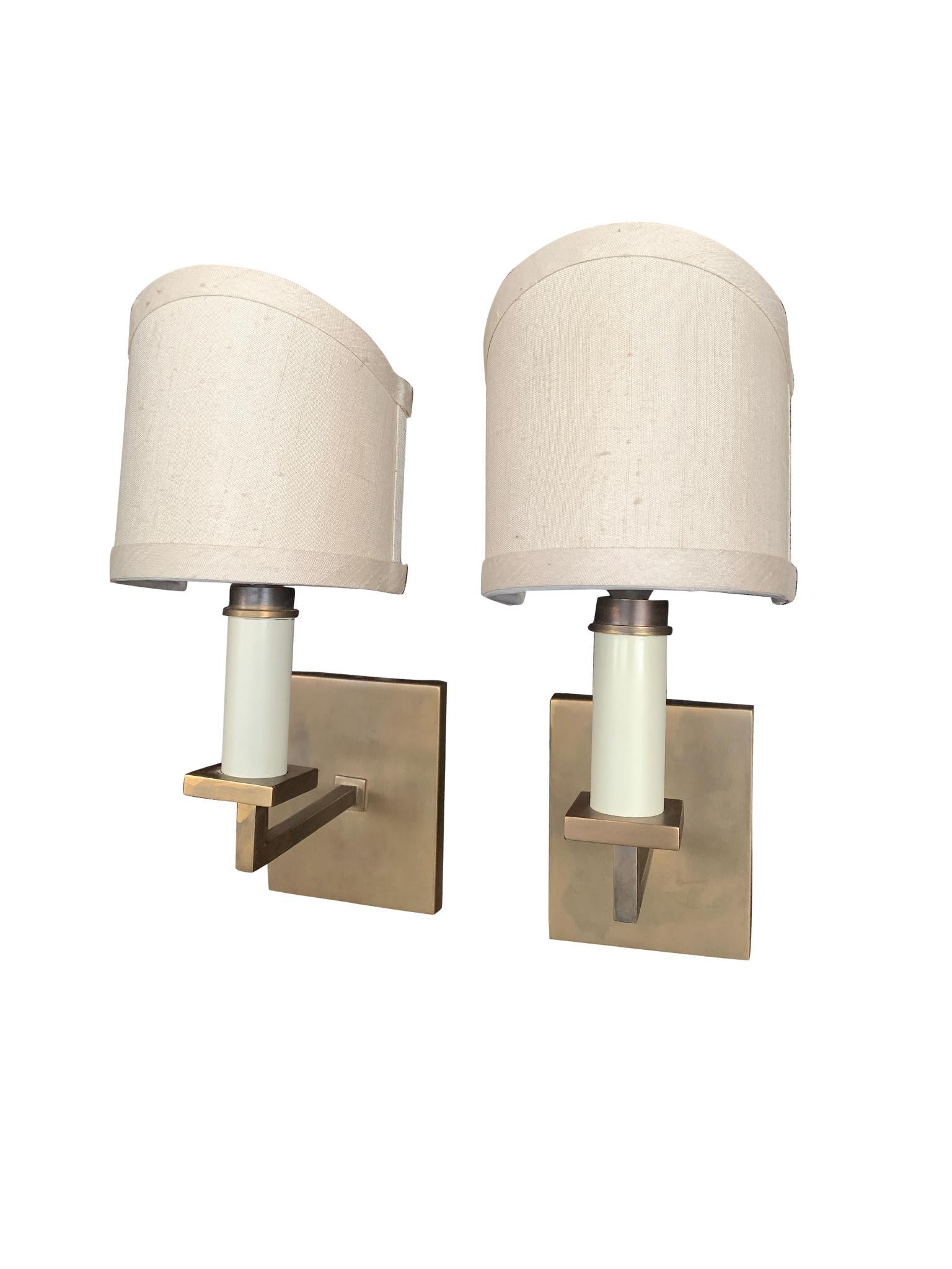We love the simplicity of these sconces, made in the 1940s in France. They are brass with candelabra-style sockets. The shades are a recent addition. They have an elegant shield structure and are comprised of silk with a resin backing. These sconces