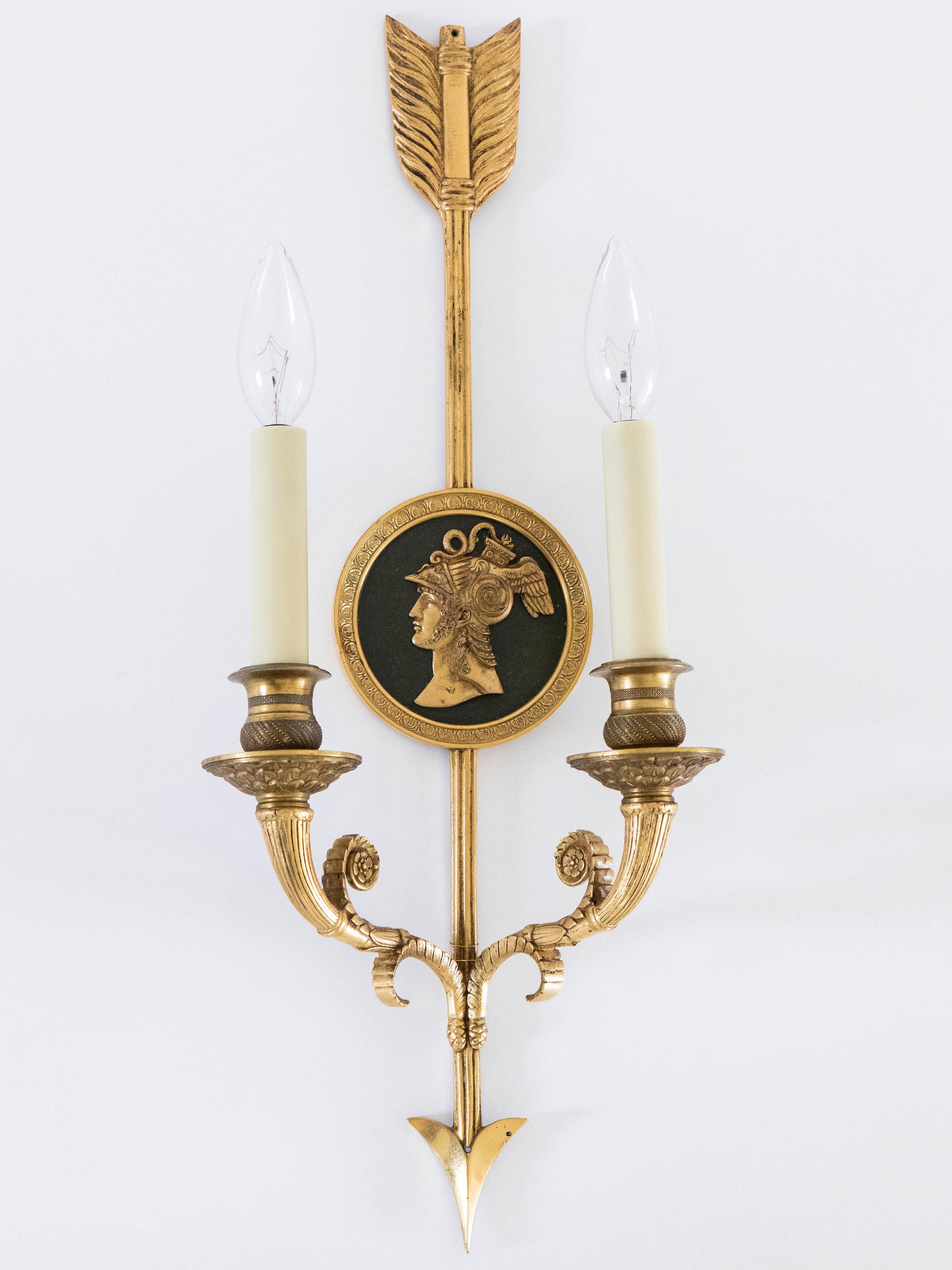 Pair of French Empire gilded bronze arrow double light sconces with medallion motif. Wired for USA, 2 sockets per lamp, 40W max per socket. New black linen shades are 4