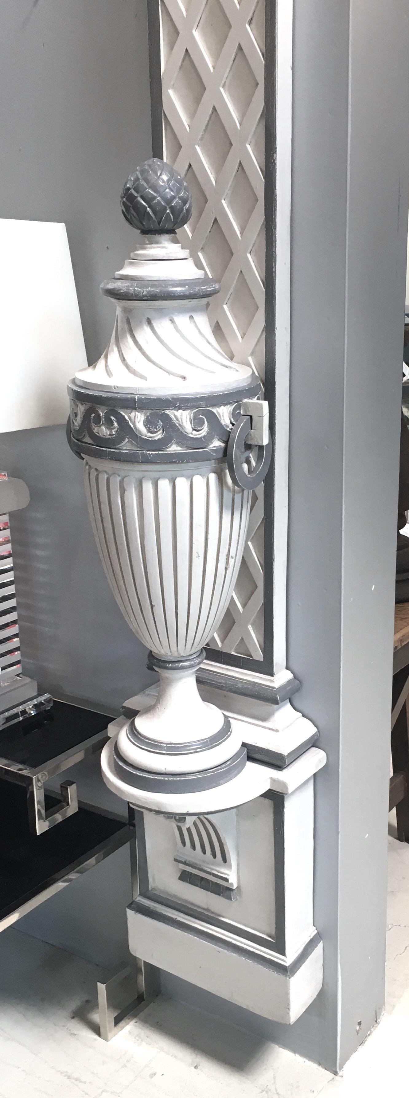 1940s French painted wall-mounted Treillage columns. Newly painted in antique white faux finish with charcoal gray detailing. Detachable decorative urns. Attached back brackets for hanging. 
This item is available to view at The Antique & Artisan