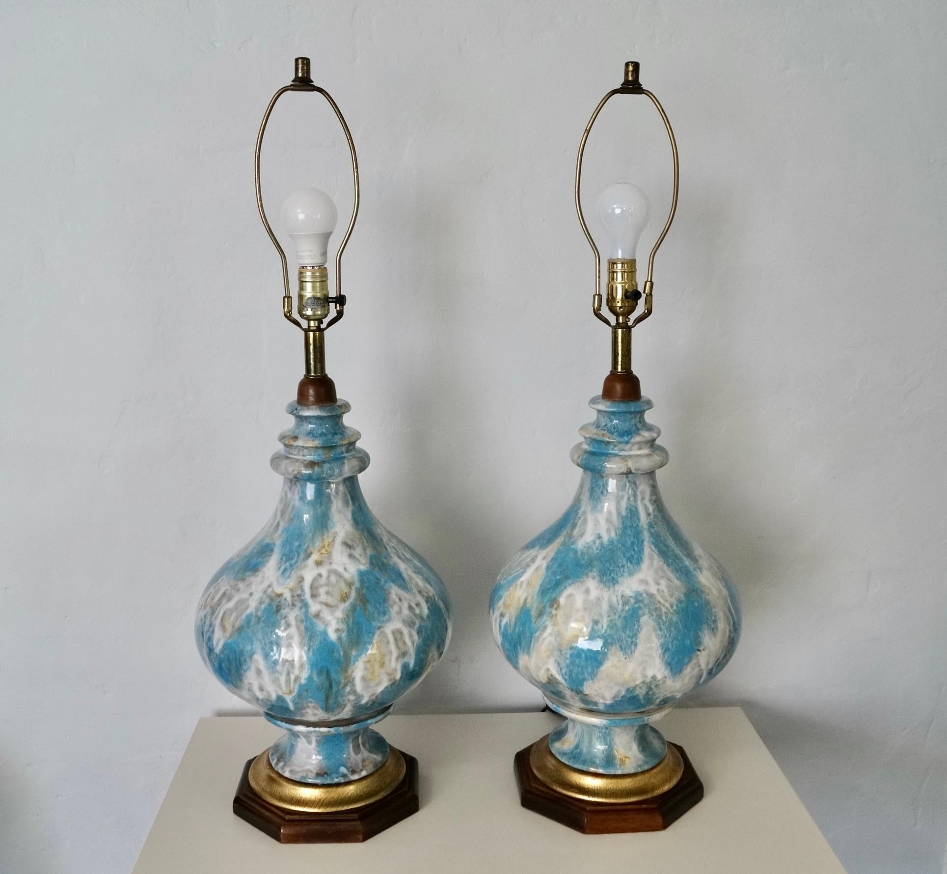Vintage pair of Mid century Modern table lamps for sale. They are both in good condition, and rare. They have a solid wood base in a walnut finish, and a gold leaf wood layered on top of the base. They are made of ceramic with a great crackle drip