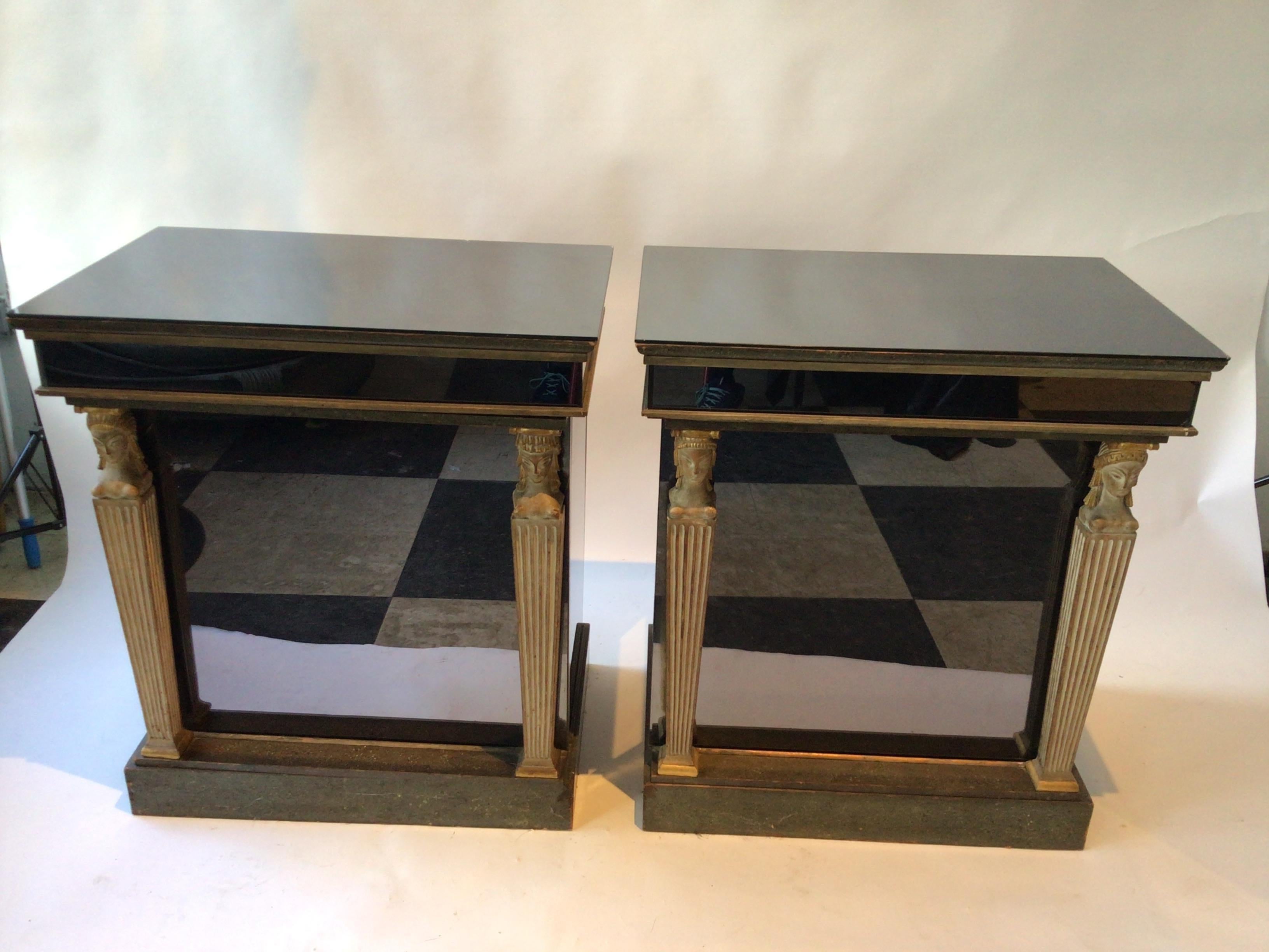 Pair of 1940s smokey mirrored cabinets with carved wood classical figures. One chip on top of glass as shown in last picture.