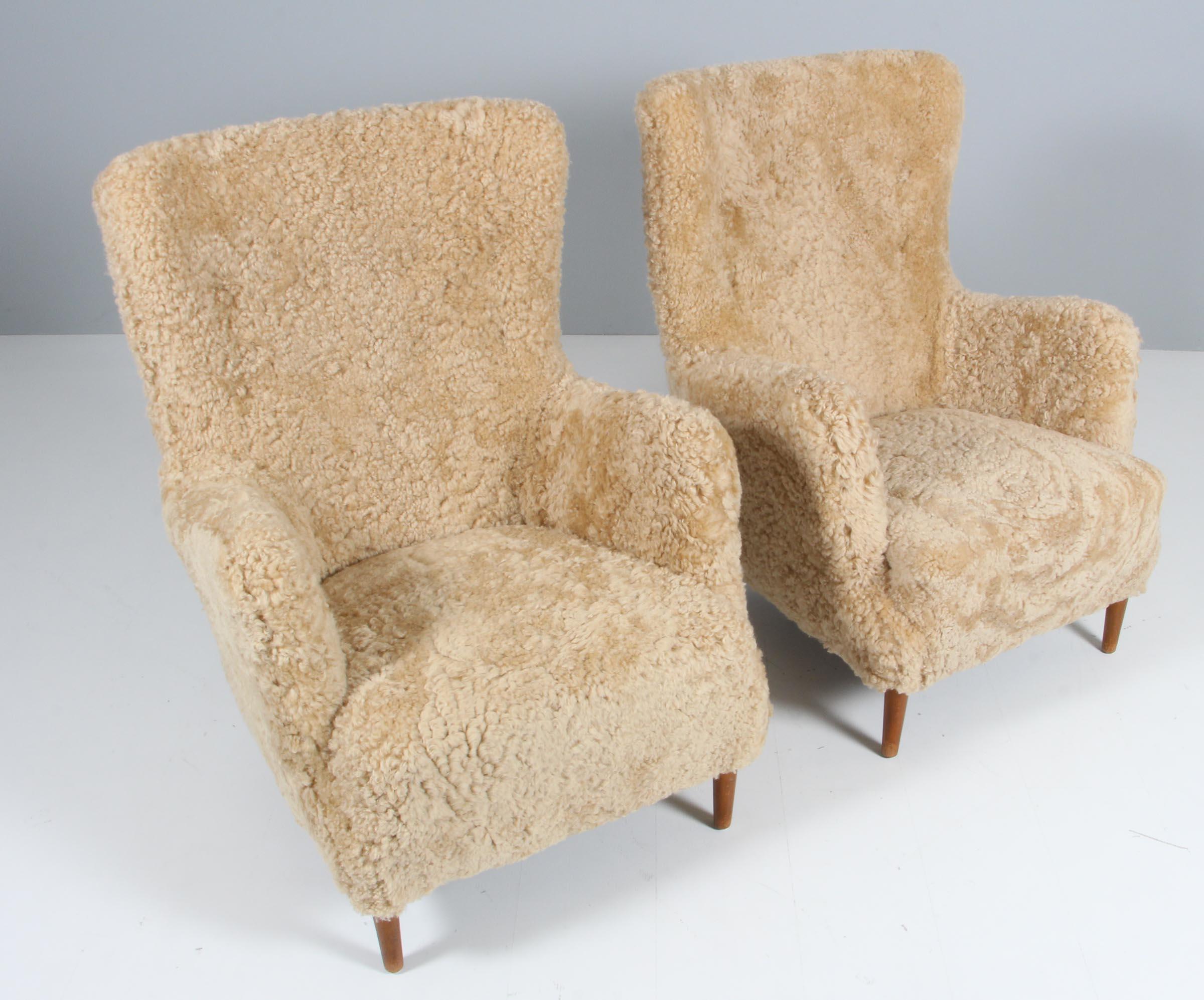 Pair of lounge chairs from the 1940s new upholstered with lambskin.

Legs of stained beech