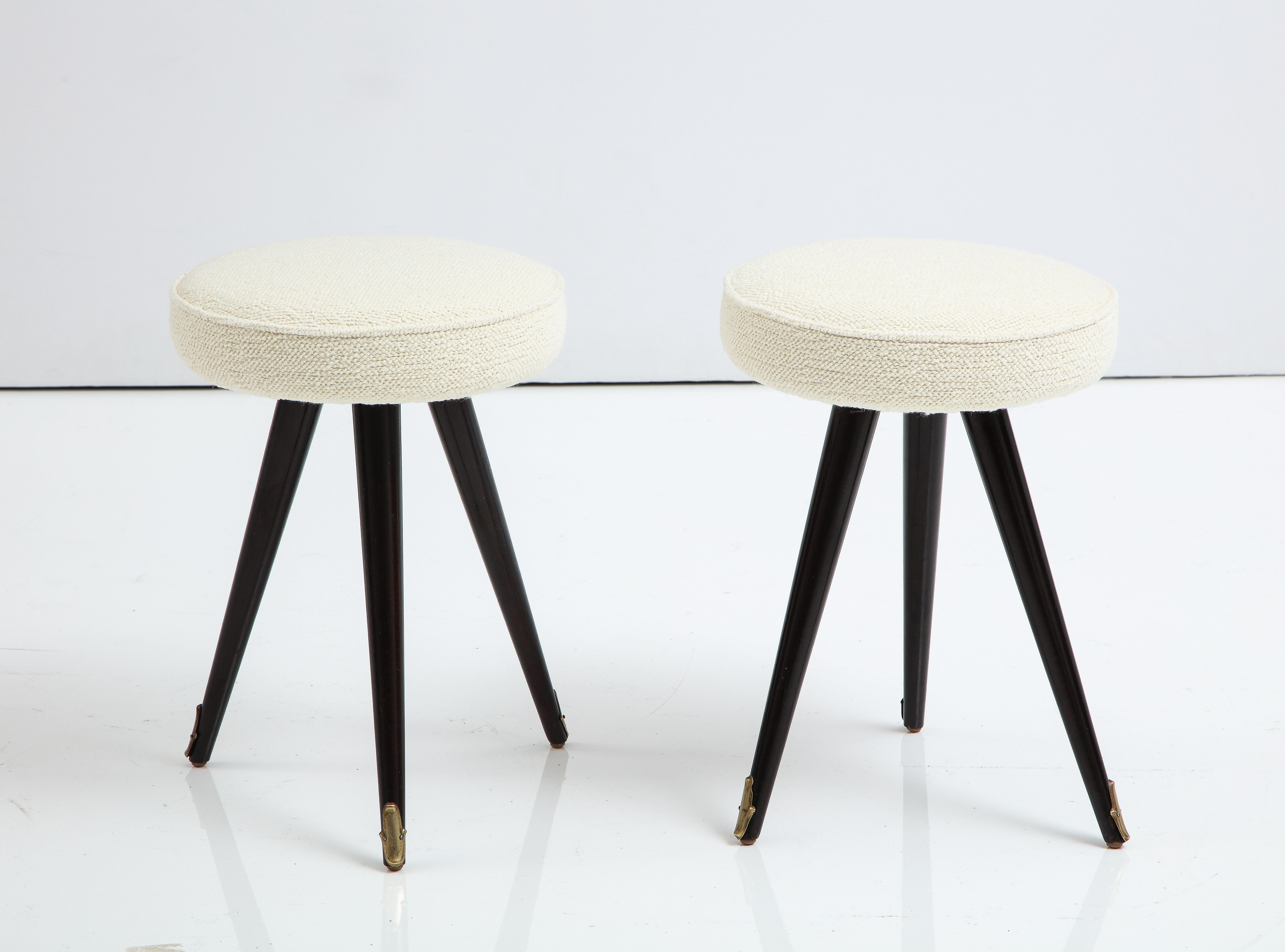 Pair of very unique Northern Italian petite stools, the tripod legs are ebonized wood, ending in elegantly shaped brass sabot. The circular seats are newly upholstered in a Belgian wool and cotton creamy textured fabric. 
Northern Italy, circa late