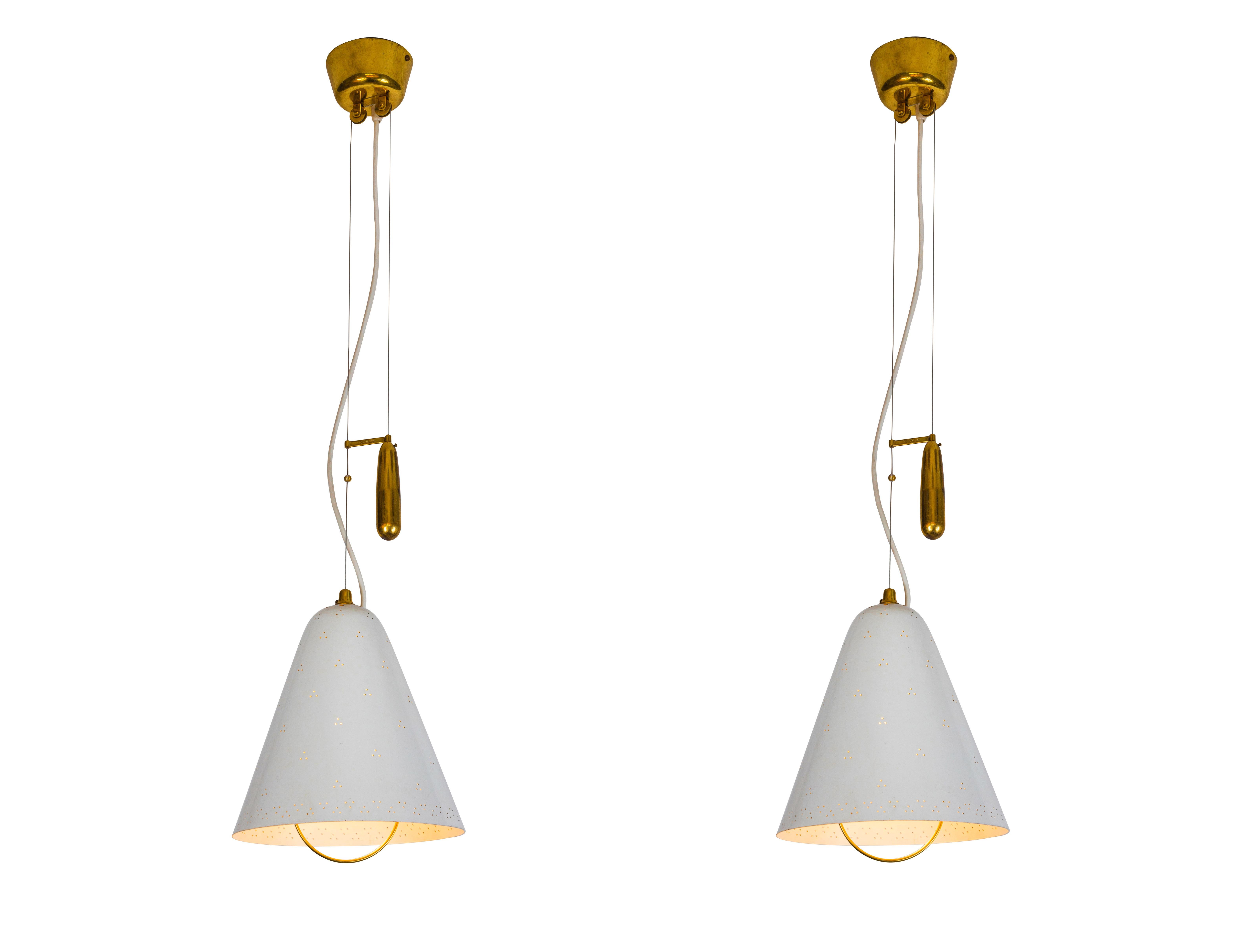 Pair of 1940s Paavo Tynell 'A1942' white counterweight pendants for Idman Oy. This rare and exceptionally pair is executed in white painted perforated metal and brass, and can be raised and lowered using its ingenious counterweight and pulley