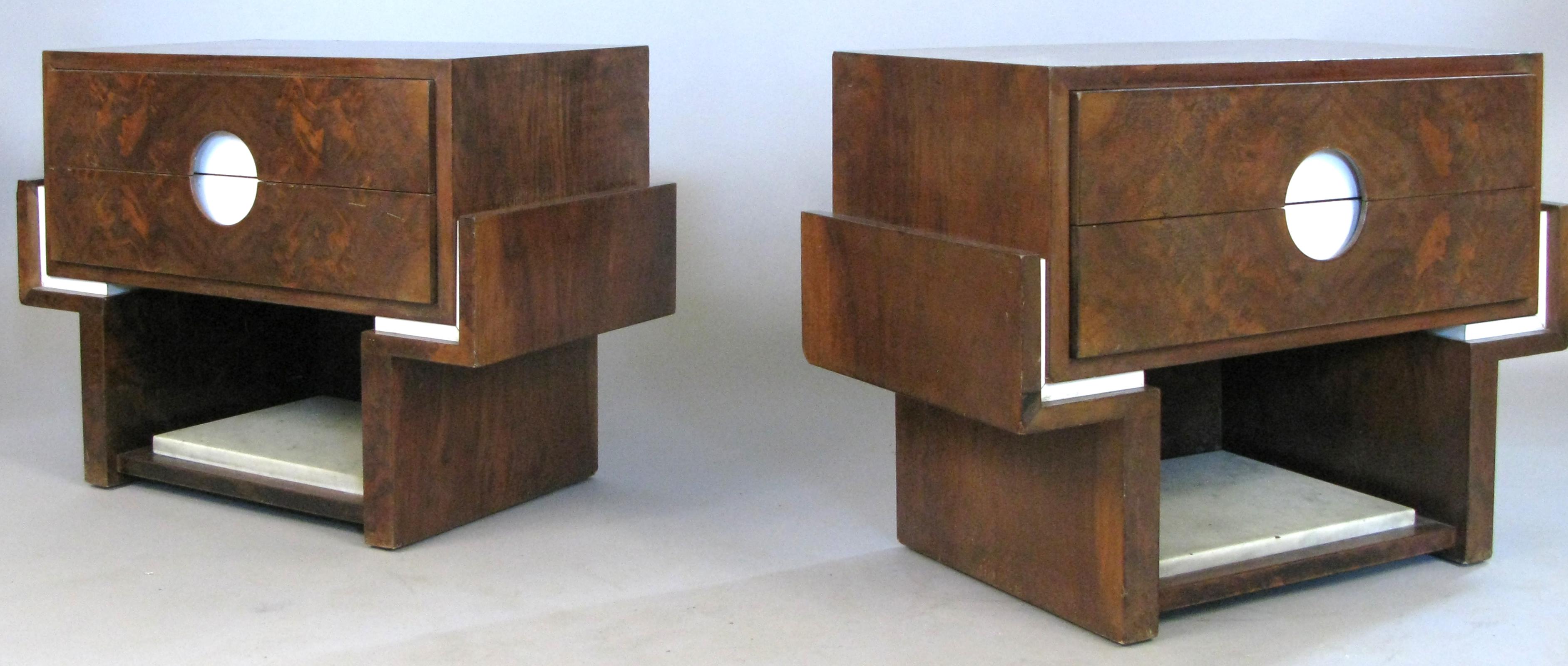 A beautiful pair of 1940s nightstands, with gorgeous bookmatched rosewood veneer, and a marble panel in the open space below the drawers. Each stand has a pair of drawers, with open cutout panels forming the handles, and white laminate trim accents.