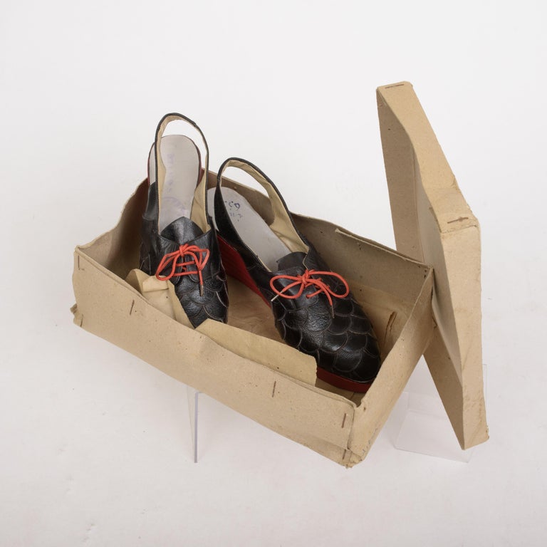 Circa 1940/1950

France

Rare pair of collector's shoes in new condition and wooden wedge heels painted in red, dating from the 1940s. Black leather upper with cutout in the shape of scales and original red laces. Cream vinyl lining and sole bearing