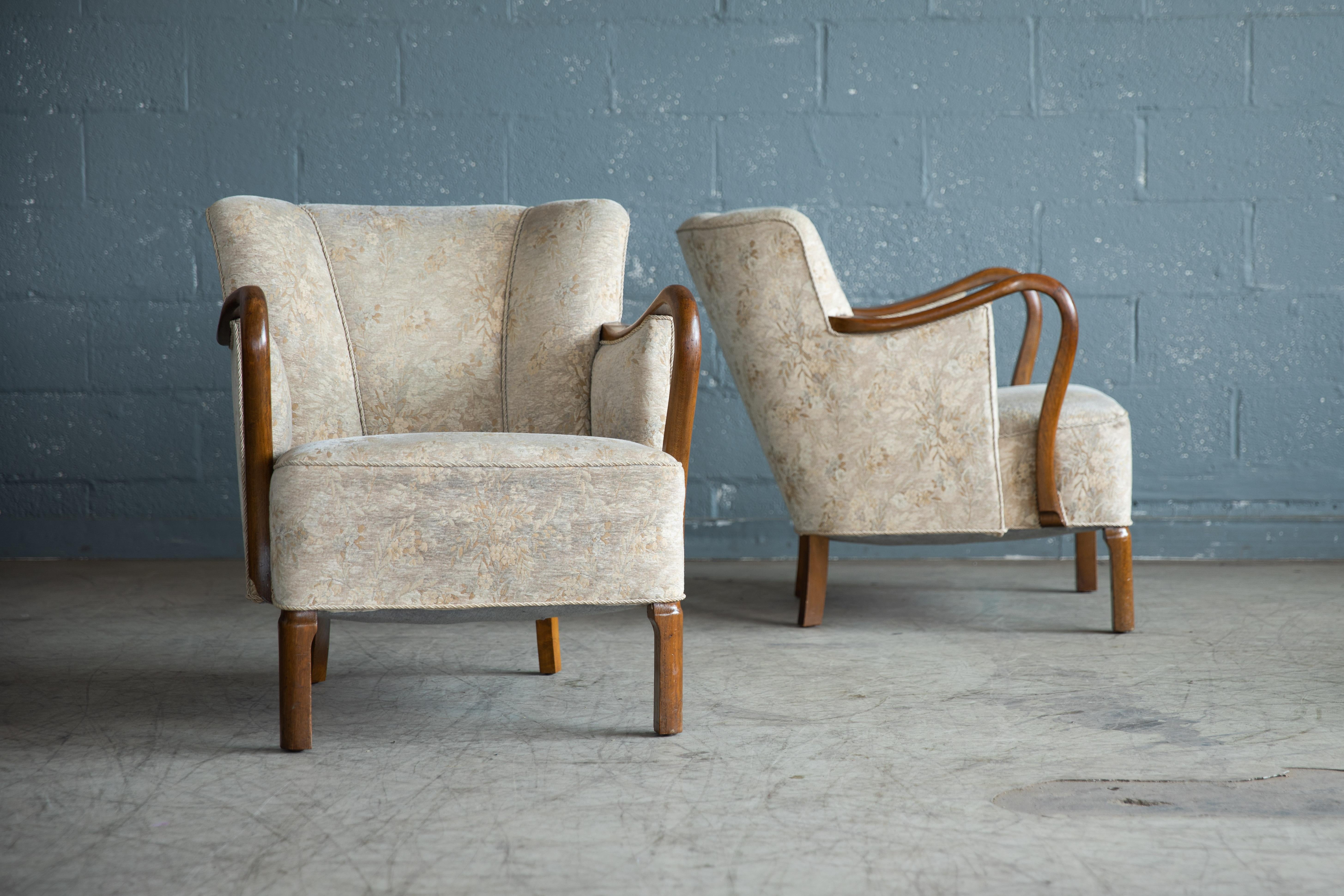 Sublime pair of lounge chairs made by Slagelse Mobelvaerk of Denmark in the 1940s with the design attributed to Viggo Boesen. These elegant chairs display the same leg design seen on other of Boesen chairs and the wooden armrests in solid oak are