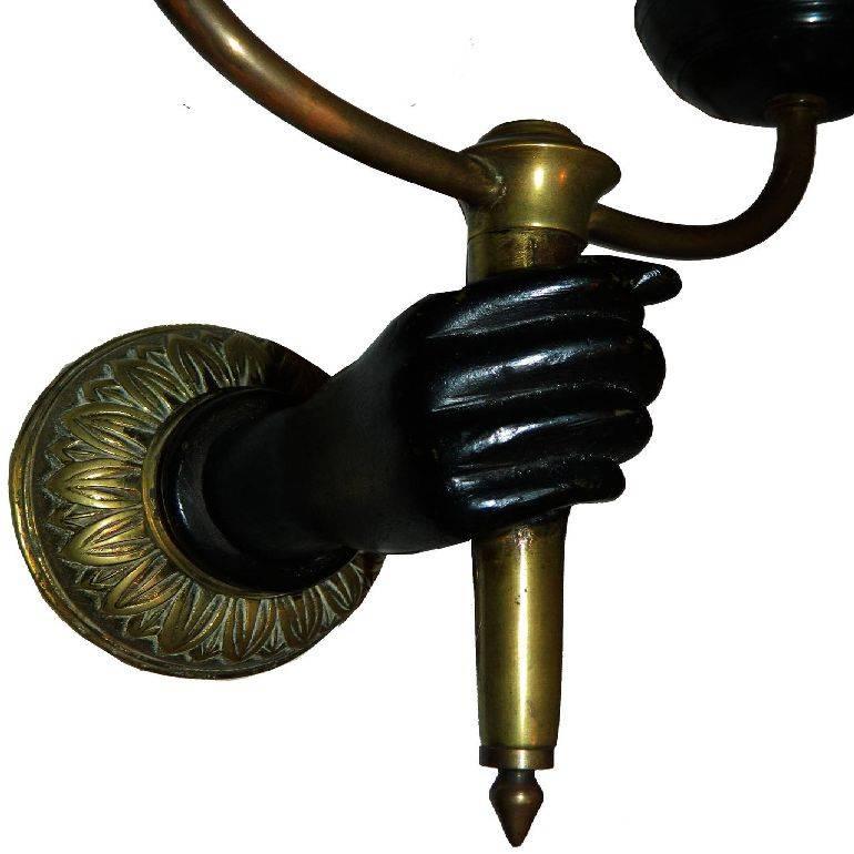 Fantastic pair of French sconces by Andre Arbus featuring a hand holding a double torch. Two patina, bronze and black lacquer. US rewired and in working condition. Four bulbs of 60 watts max. Backplate: 3.3/8