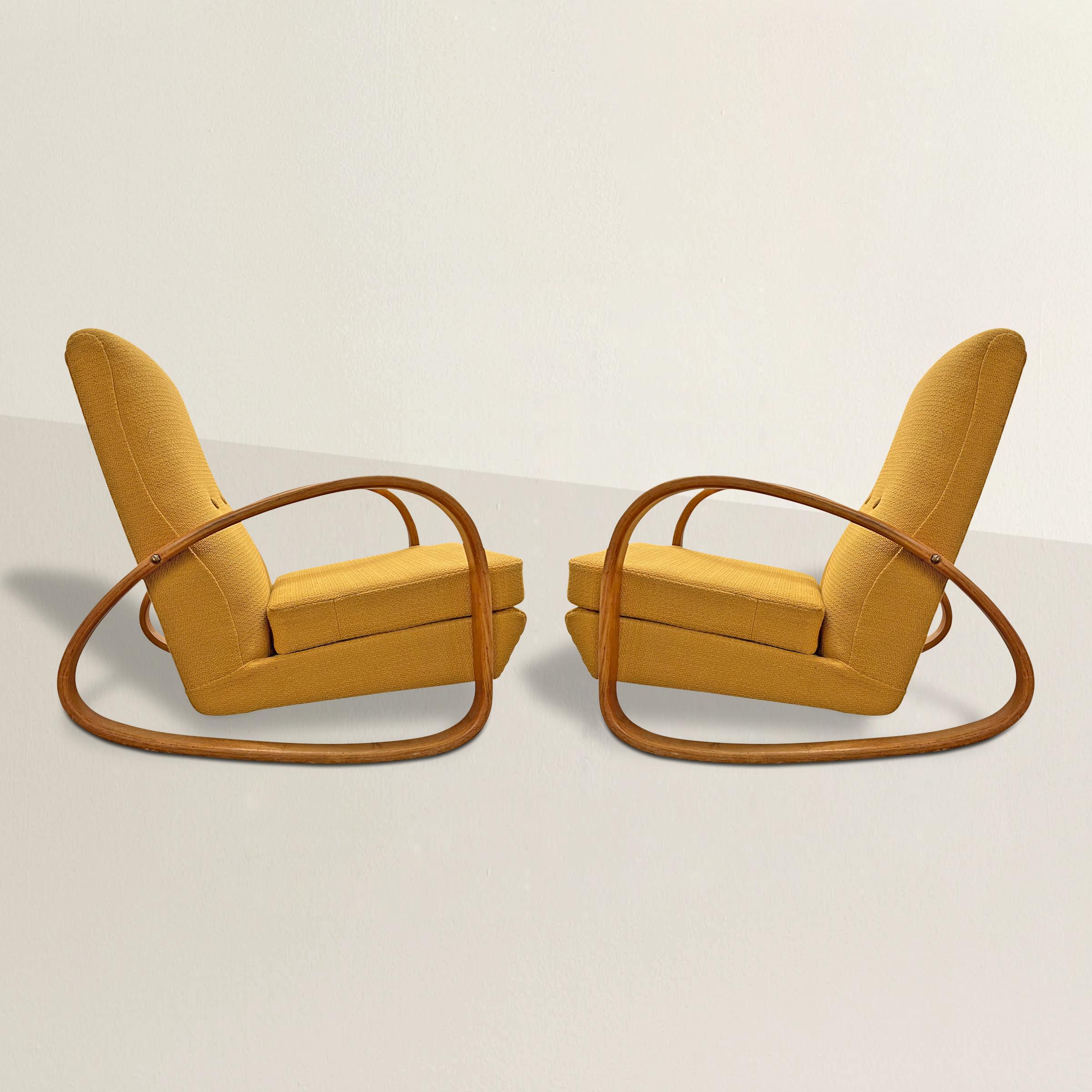 A chic pair of mid-20th century American rocking armchairs with continuous bent oak arms that turn into the rocking stretchers, and newly upholster in a period-appropriate goldenrod chunky wool fabric. These chairs sit like a lounge chair with the