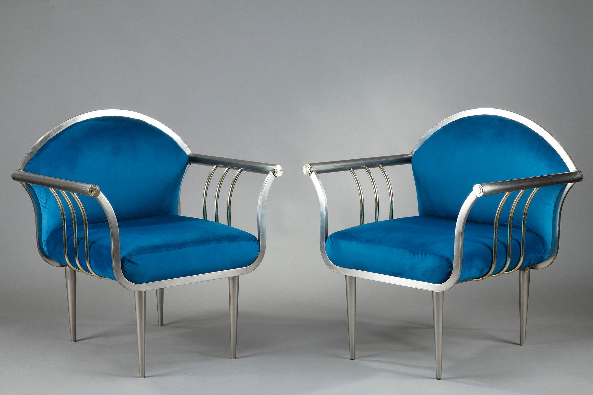 Pair of chromed steel armchairs and upholstered in peacock blue velvet. They rest on four tapered legs, the convex arms are connected to the seat by three golden bars. The tubular structure in chromed steel is gilded at the level of the buttons of