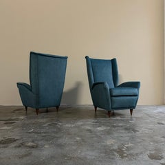 Paire de fauteuils des années 1950, piètement en bois italien de haute qualité et tissu bleu pétrole.