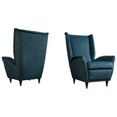 Paire de fauteuils des années 1950, piètement en bois italien de haute qualité et tissu bleu pétrole.