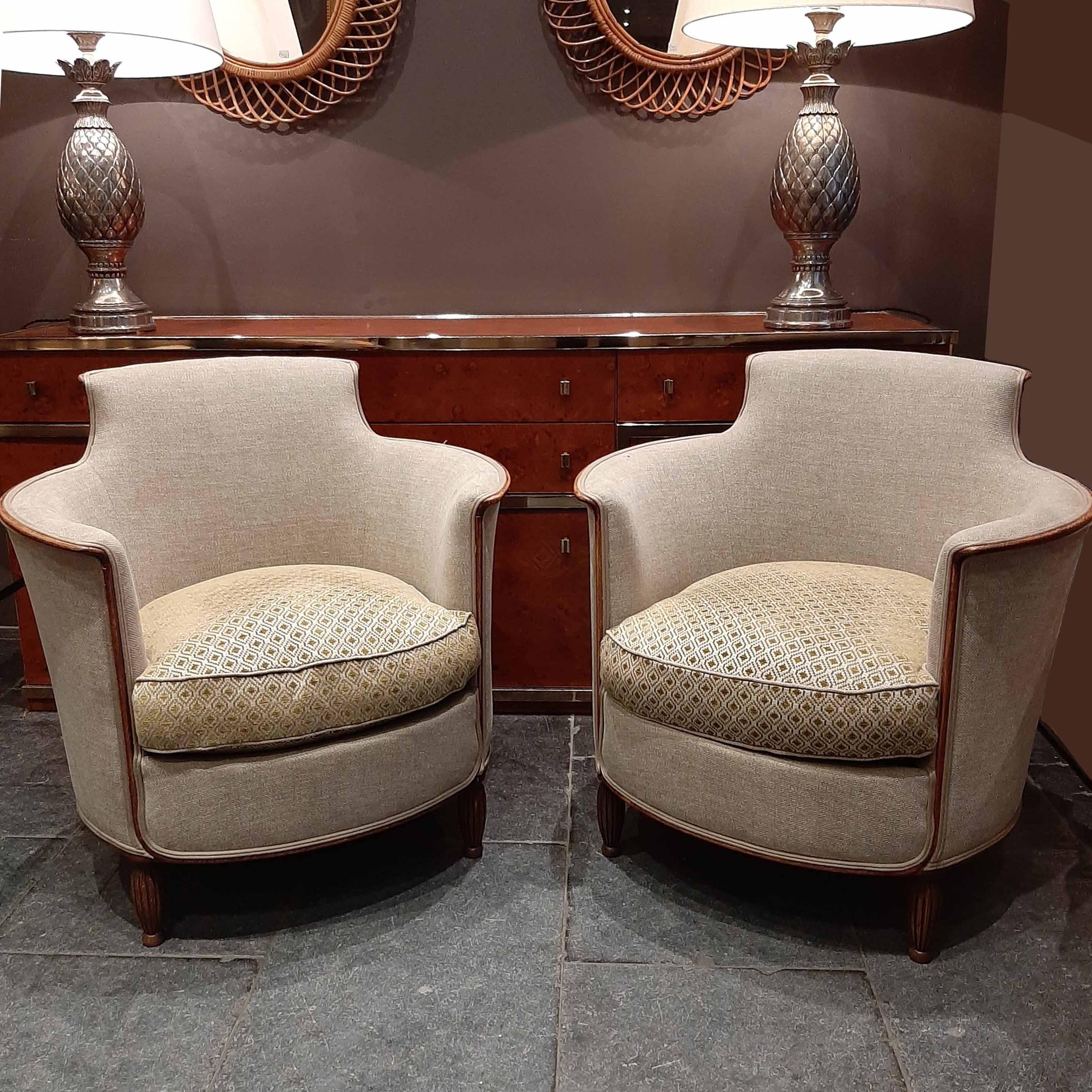 Pair of 1950s armchairs. These charming fifties chairs have a lovely round shape. They are re-upholstered in a new art deco style fabric in the color beige with green details. The legs and around the body of the chairs a lovely walnut wooden