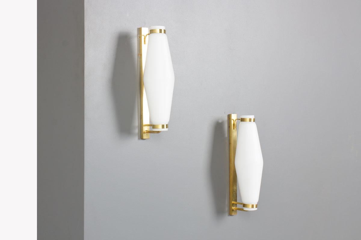 Elegante y emblemática del diseño italiano de posguerra, esta pareja de apliques editada por Stilnovo combina latón y cristal opalino en una composición refinada y minimalista.

El contraste entre el cálido latón patinado y la suave difusión del