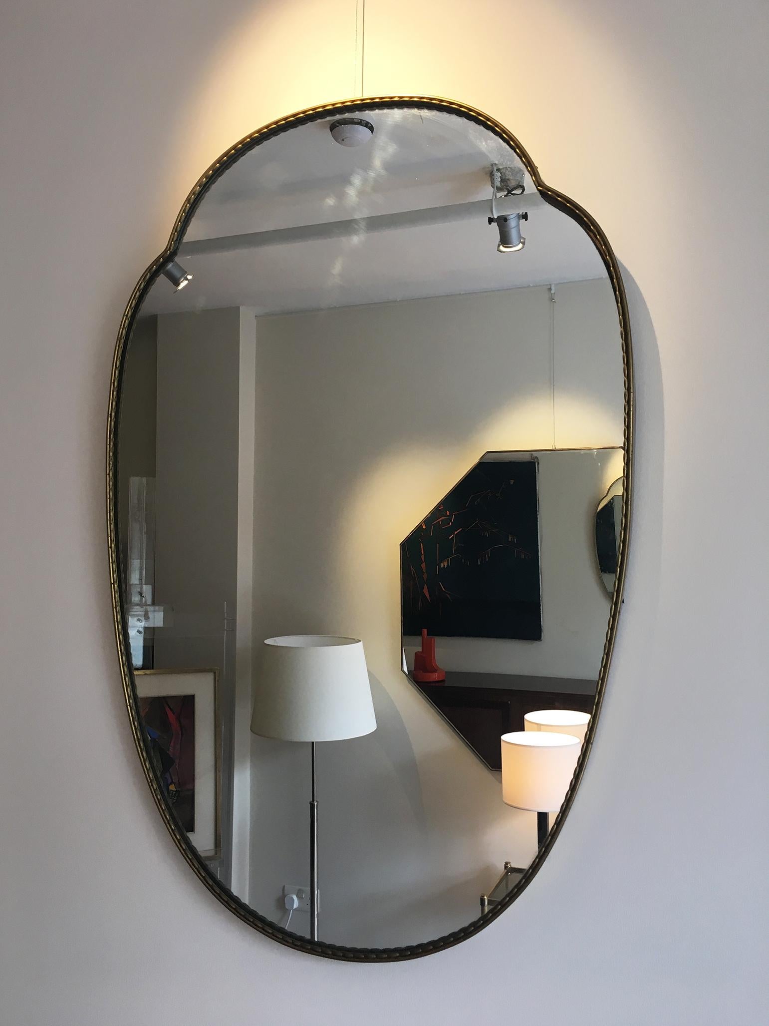 A pair of brass shield shaped mirrors with an interesting rice-like beading,
Italy, circa 1950.