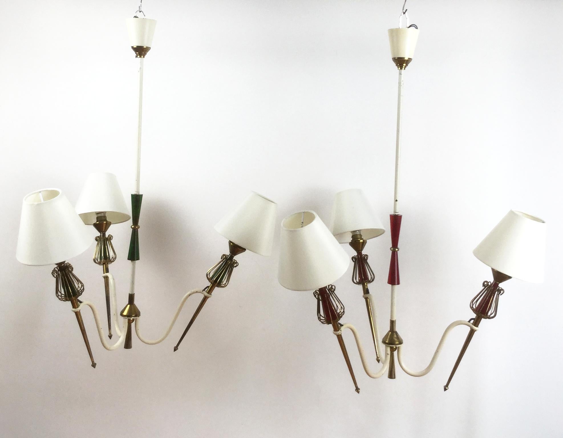 1950 Pair of French three lights pendant lamps by Maison Lunel Royale Lumière, each one with a beautiful brass finish and a decorative central piece in a translucent red or green bakelite.