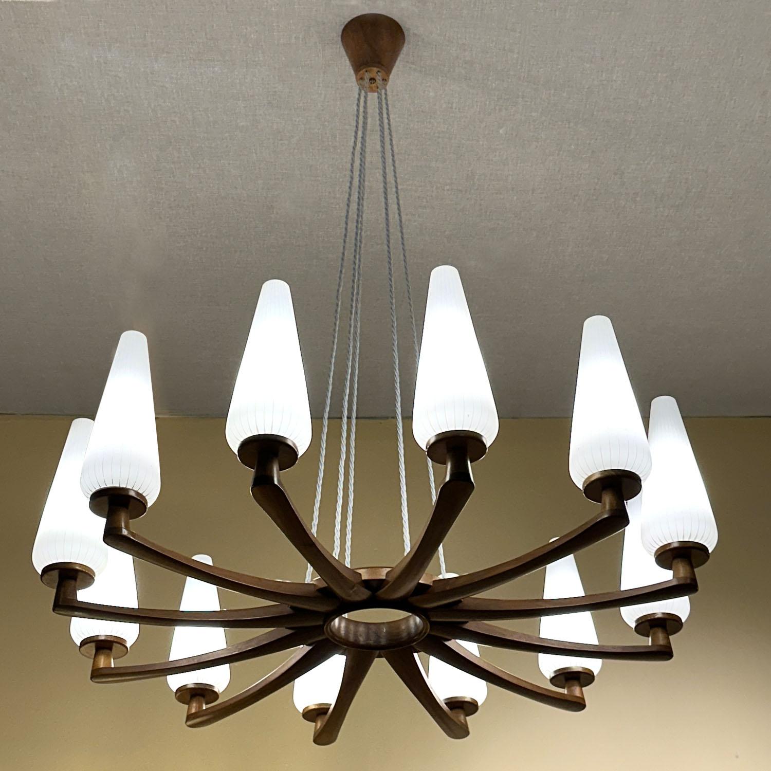 Paire de grands lustres conçus par Design/One et Östen Kristiansson en 1951 pour la société suédoise Luxus Vittsjö. Elles sont réalisées dans un cadre en noyer portant douze bras avec des abat-jours en verre opalin qui, lorsqu'ils sont allumés,