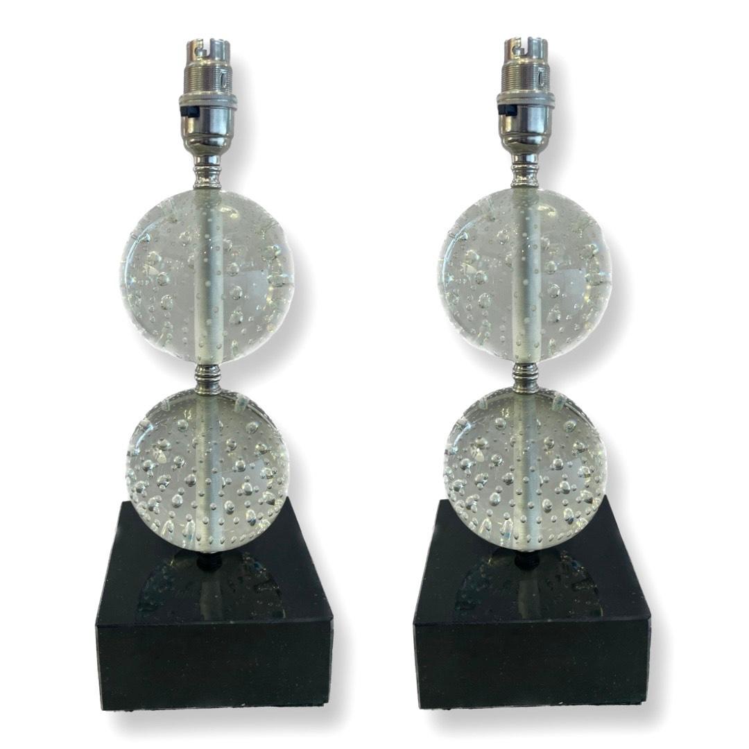 Paire exquise de lampes de table en cristal des années 1950.

Ces lampes captivantes présentent deux sphères de cristal gracieusement perchées sur des bases en pierre noire polie, exhalant un sentiment d'opulence et de sophistication. Les sphères de