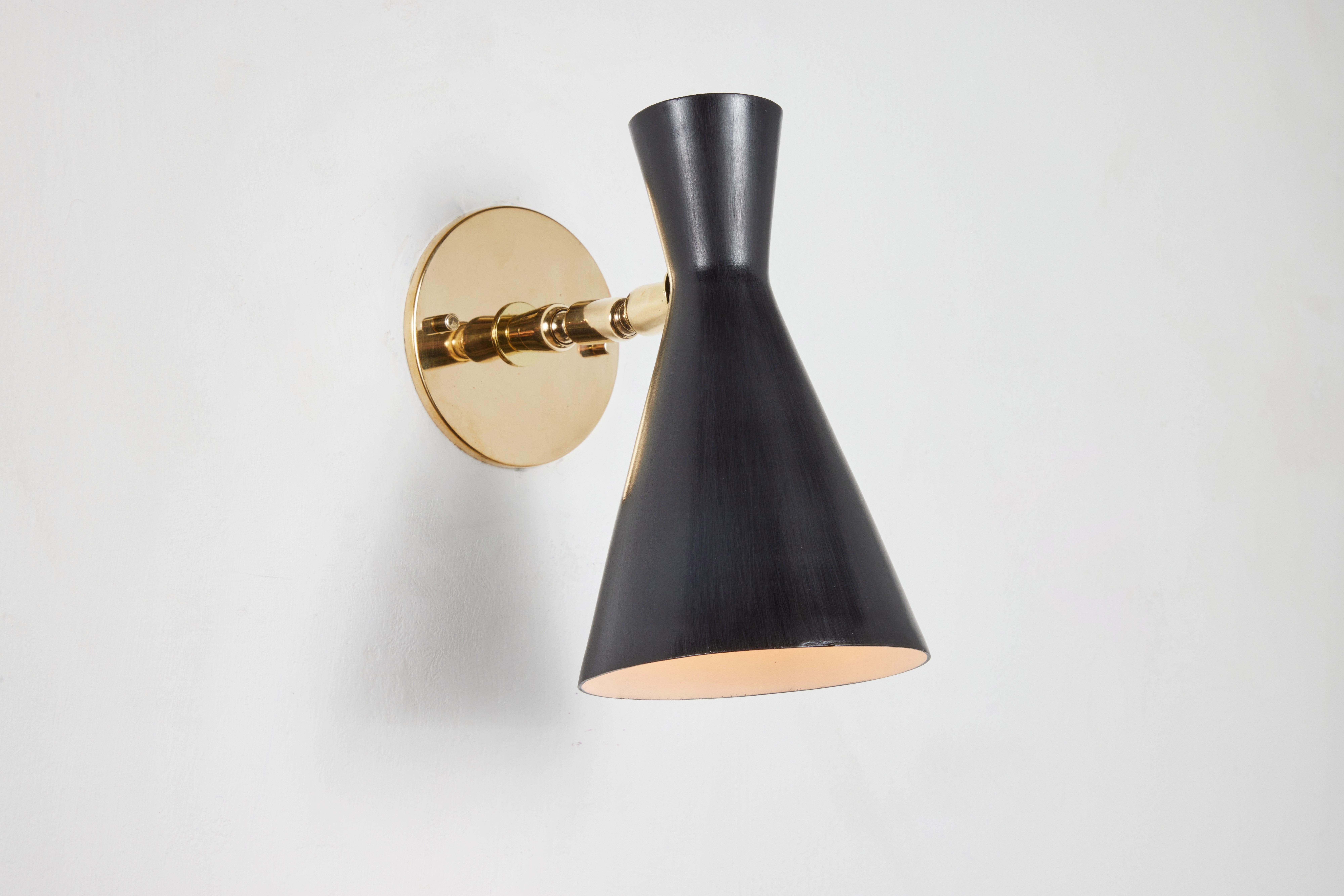 Pair of 1950s Diabolo sconces by Giuseppe Ostuni for O-Luce Executed in black painted metal and brass. A sculptural and refined wall lamp reminiscent of a contemporary midcentury Stilnovo design, the shade rotates freely on the trademark Oluce