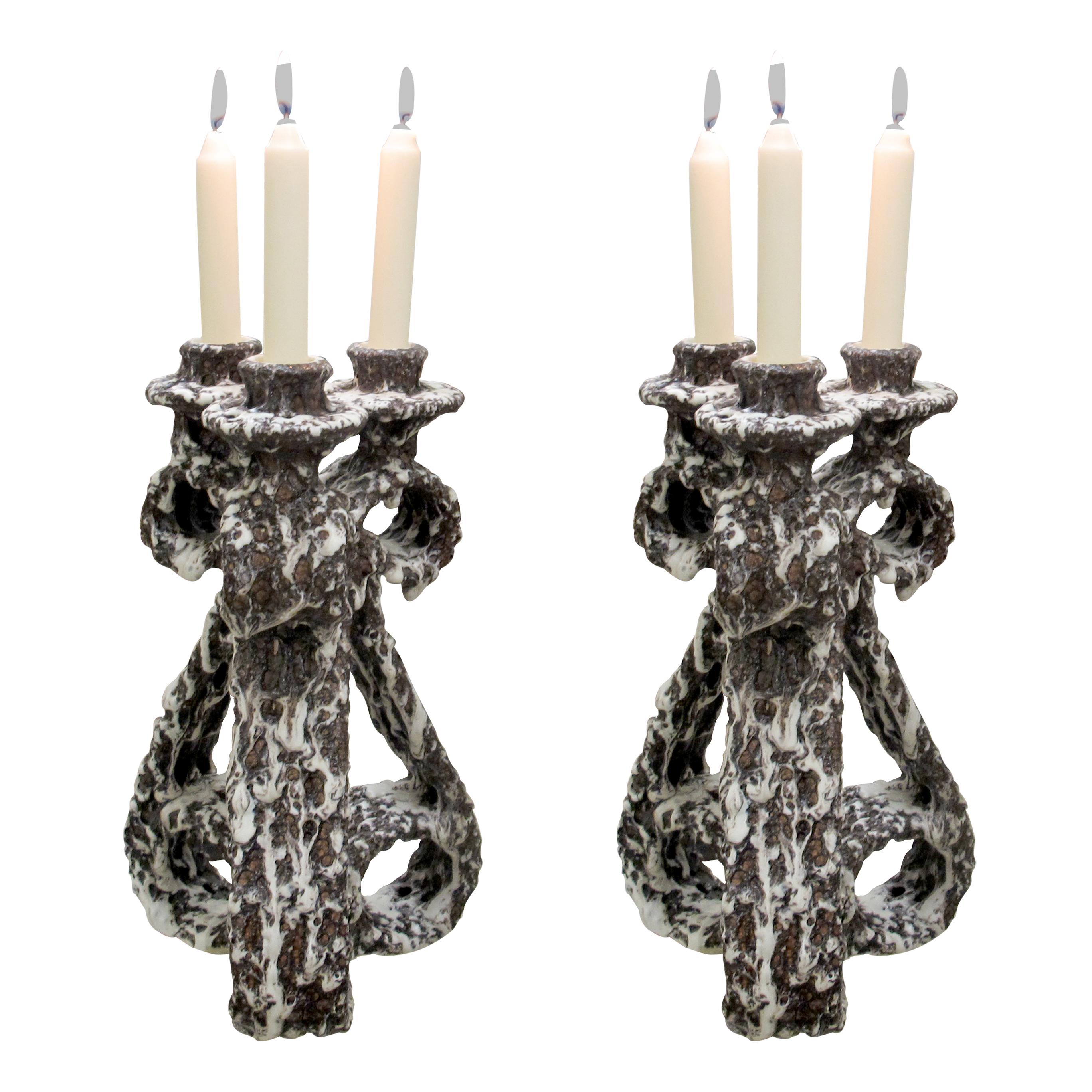 This is a pair of collectable French fat lava ceramic candlesticks from the 1950s, made in Vallauris by Marius Giuge. Each piece features a sculptural, textured design with a bold, organic form typical of the mid-century style from the region. The