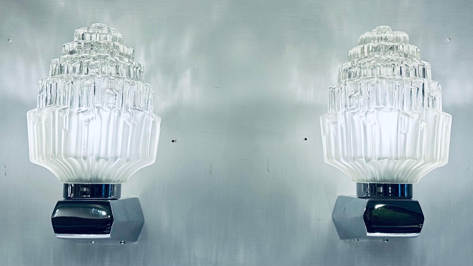 A stunning pair of wall lights or sconces manufactured during the 1950s by EJS Lighting Corp of Compton, California USA.

The glass lampshade has been formed to recreate a cut crystal staggered with friosted glass at the base to disguise the