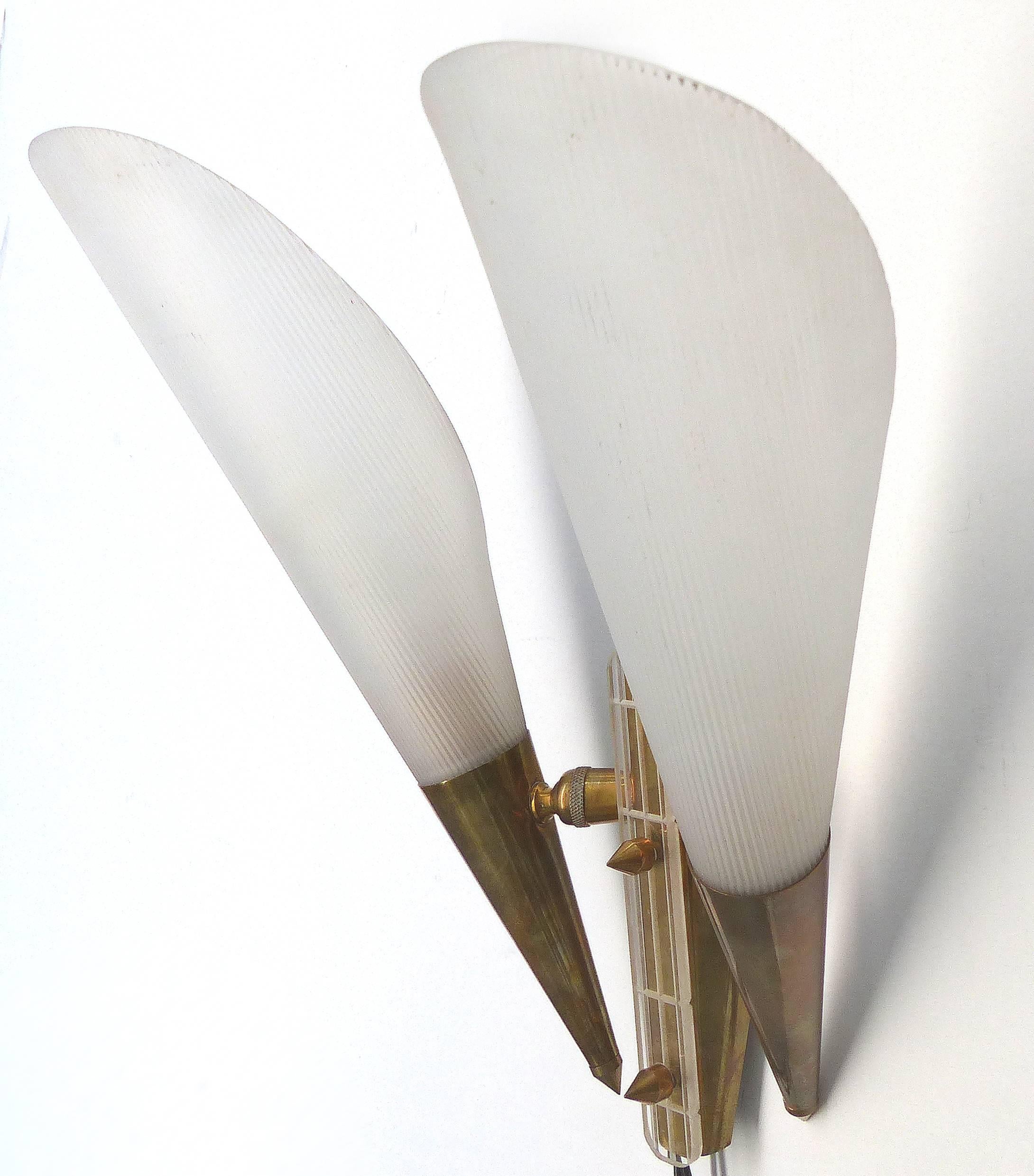 Nous proposons à la vente une paire d'appliques murales françaises ajustables à deux lumières en laiton et plexiglas. Les bras peuvent être orientés pour diriger la lumière selon les besoins. Les abat-jour de forme conique sont en acrylique strié.