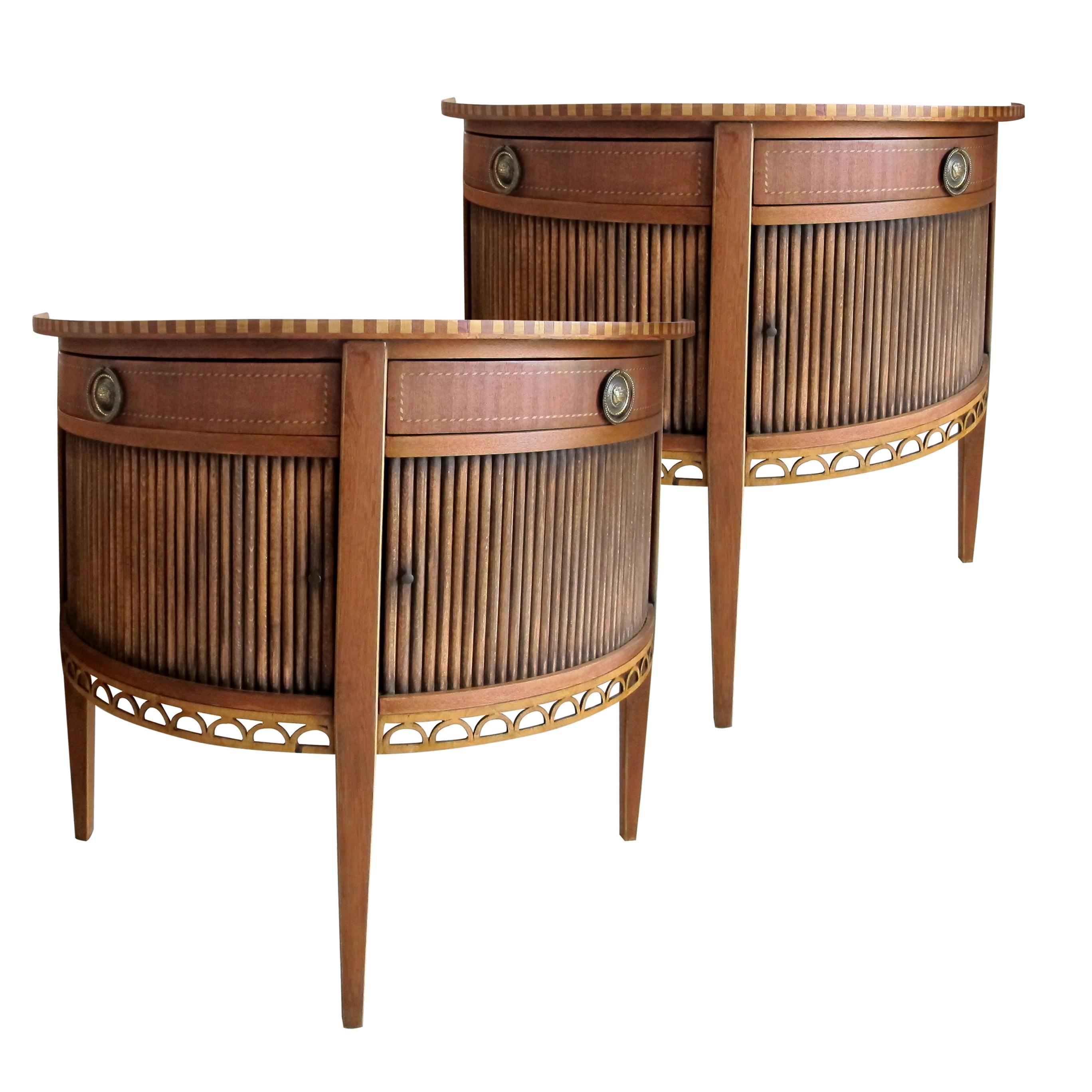 A pair of elegant mid century French side or end tables with feature tambour doors. The two top drawers swivel from the centre outwards. The tables are decorated with a marquetry trim on the top and on the drawers which feature their original brass