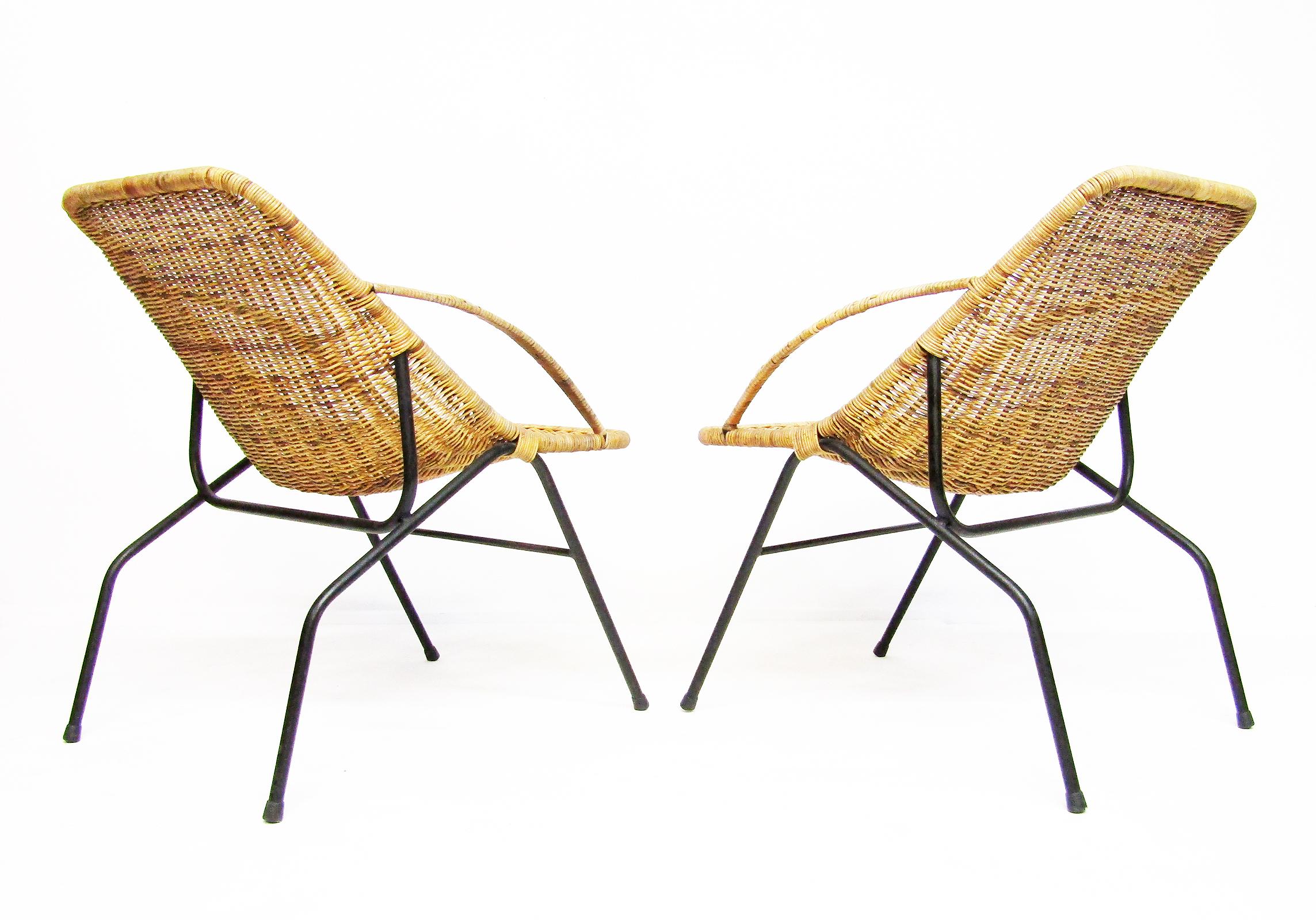 A pair of graceful 1950s French armchairs in rattan wicker and tubular steel, in the style of Jaques Adnet.

The dynamic modernist frame evokes gazelle's legs, the wicker seats providing strong support and ergonomic comfort.

With patina