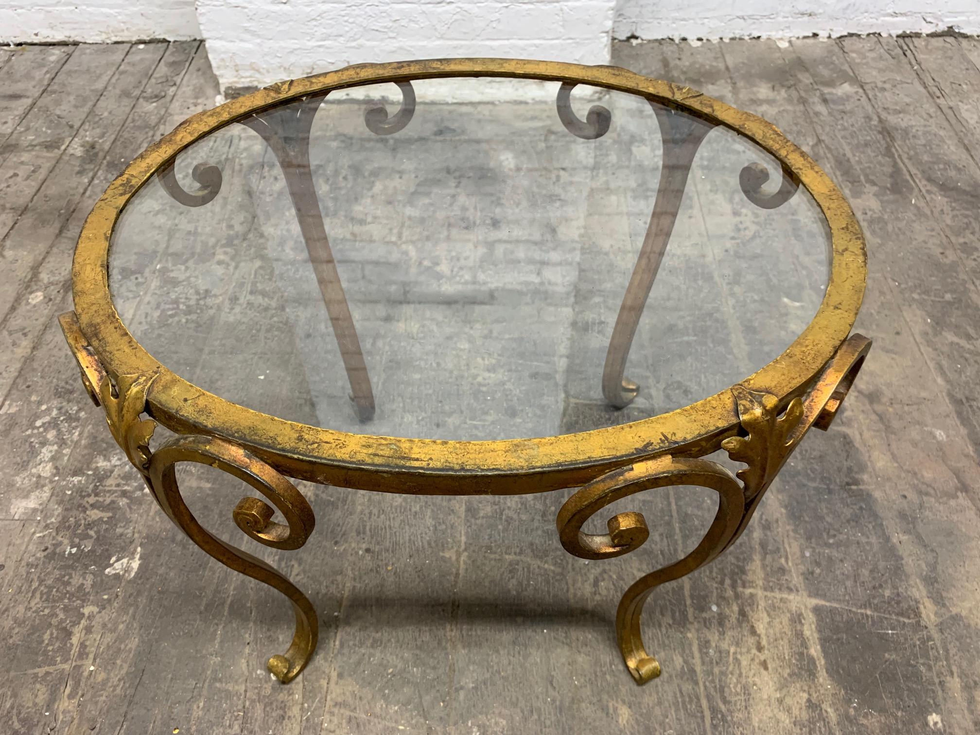 Pair of 1950s French gilt wrought iron glass top side tables. Oval shaped tables with a decorative wrought iron frame.